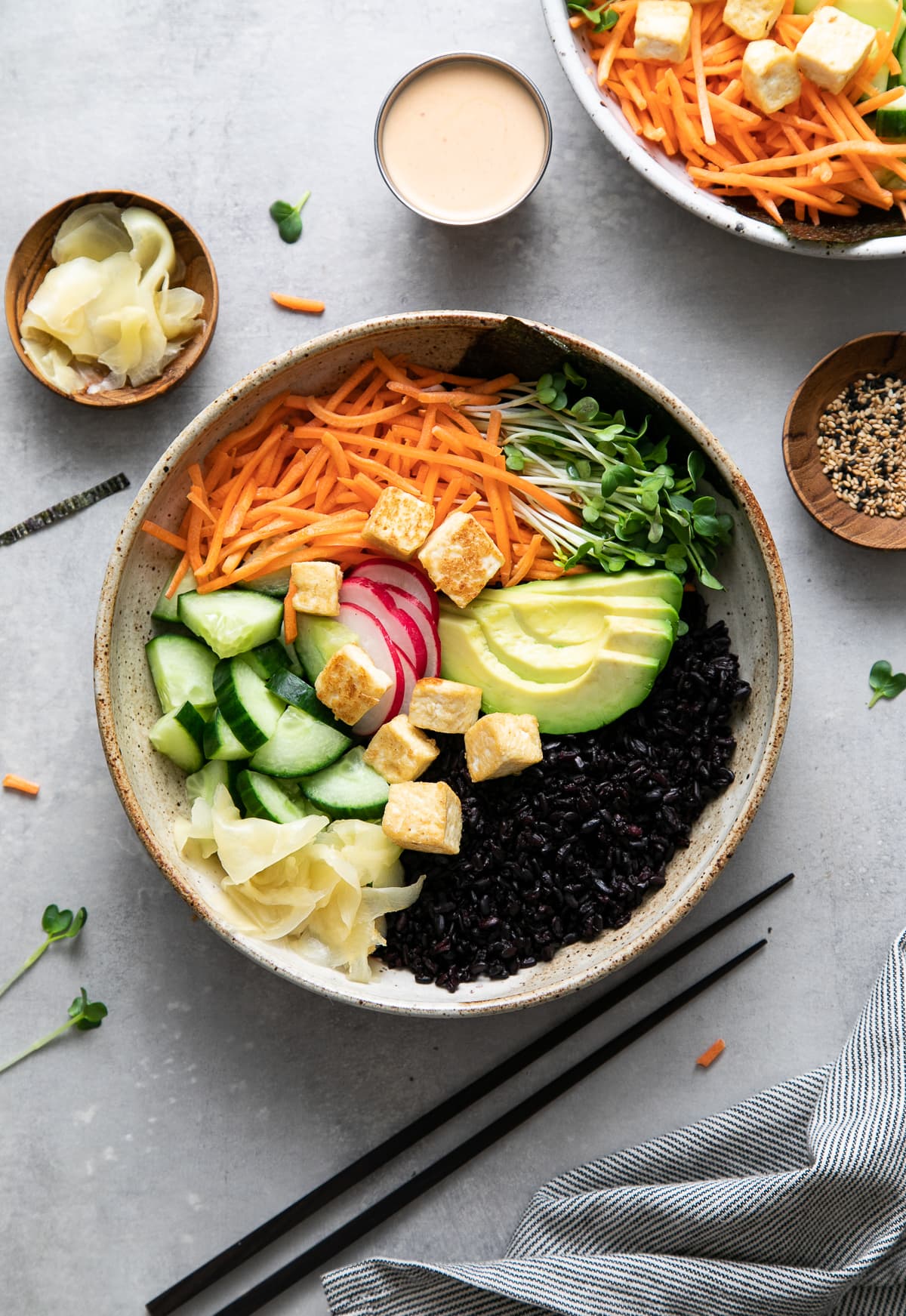 side angle view of freshly made vegan sushi bowl before adding creamy sauce with items surrounding.