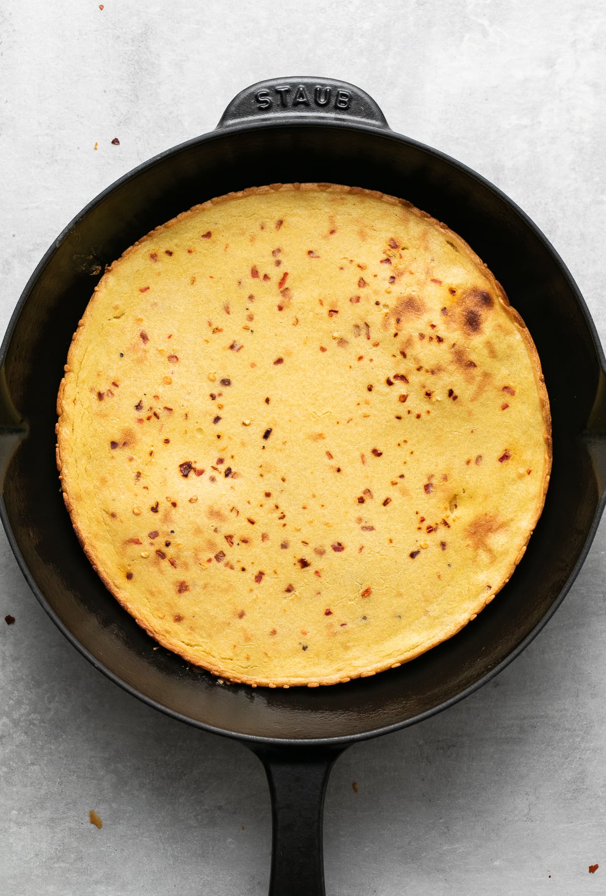 top down view of socca flatbread in a cast iron skillet.