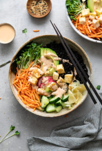 top down view of vegan sushi bowl topped with creamy dynamite sauce with items surrounding.