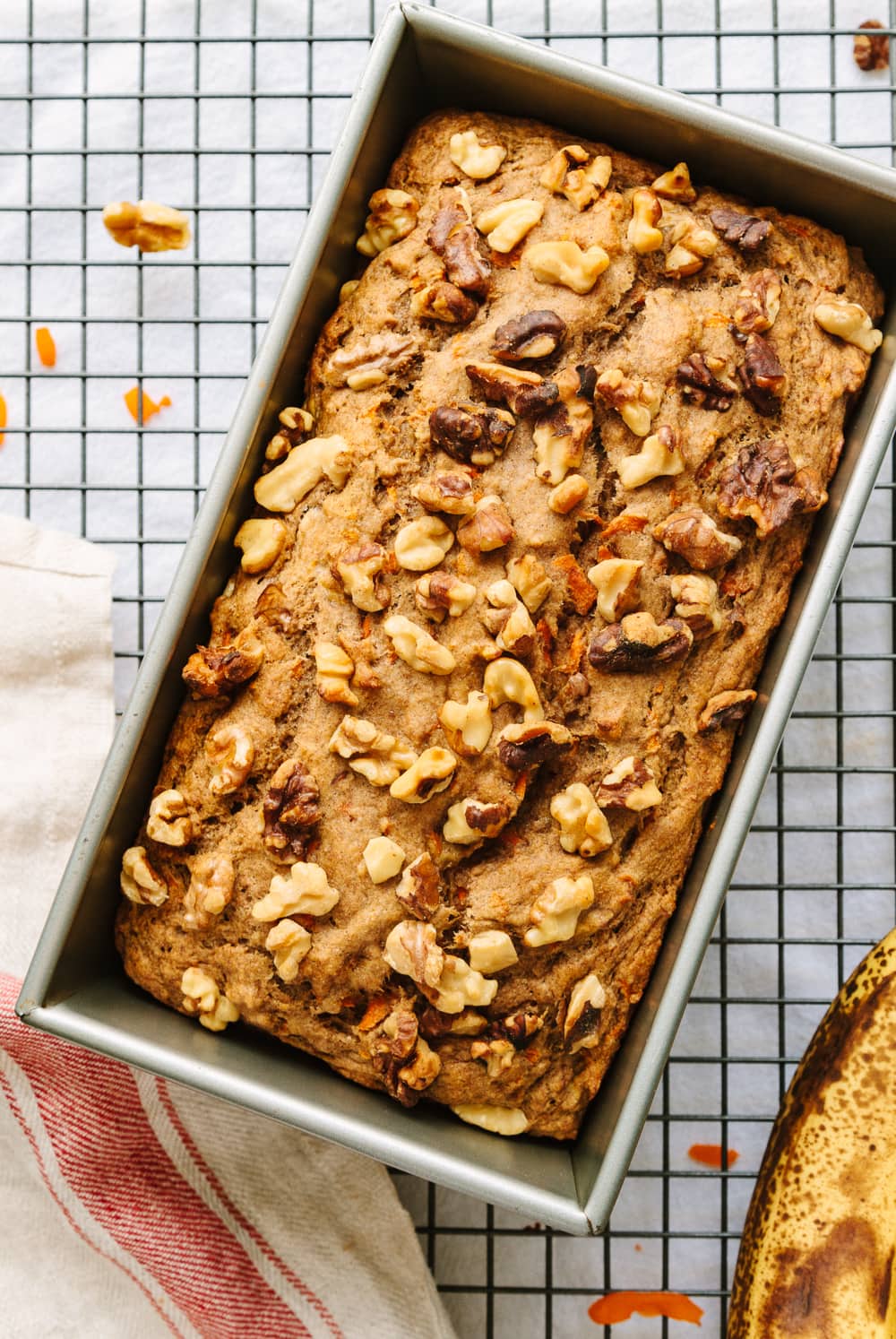 top down view of vegan carrot banana bread in a loaf pan cooling on a wire rack.