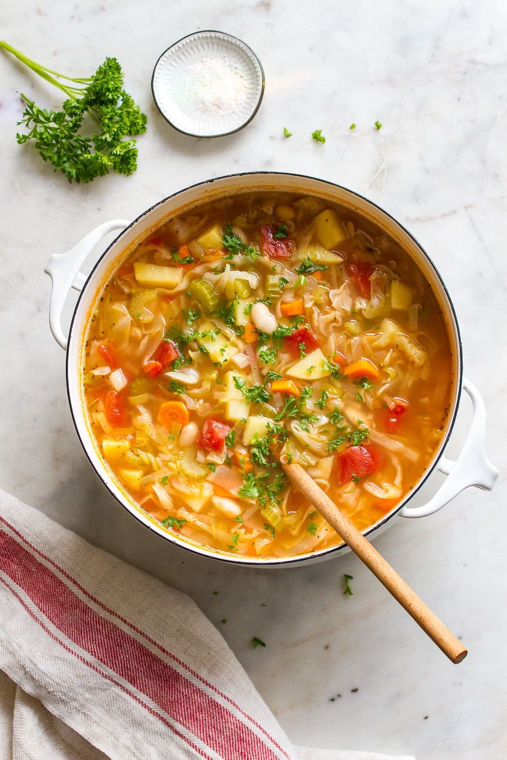 top down view of a pot filled with freshly cooked cabbage, potato and white bean soup in a large pot.