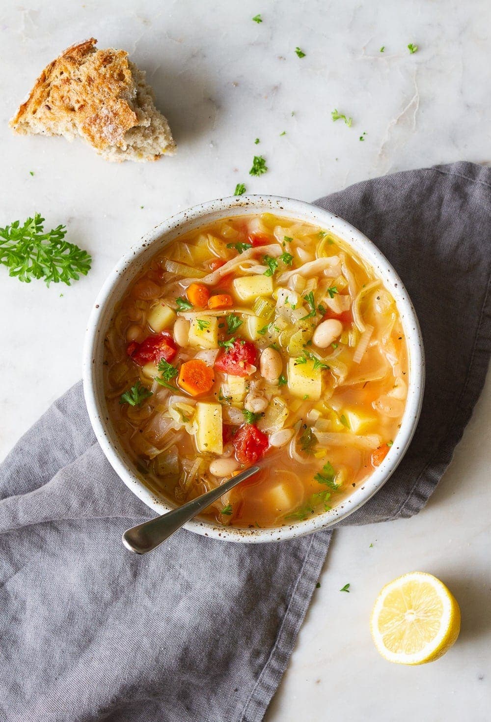 top down view of a bowl filled with cabbage, potato and white bean soup.