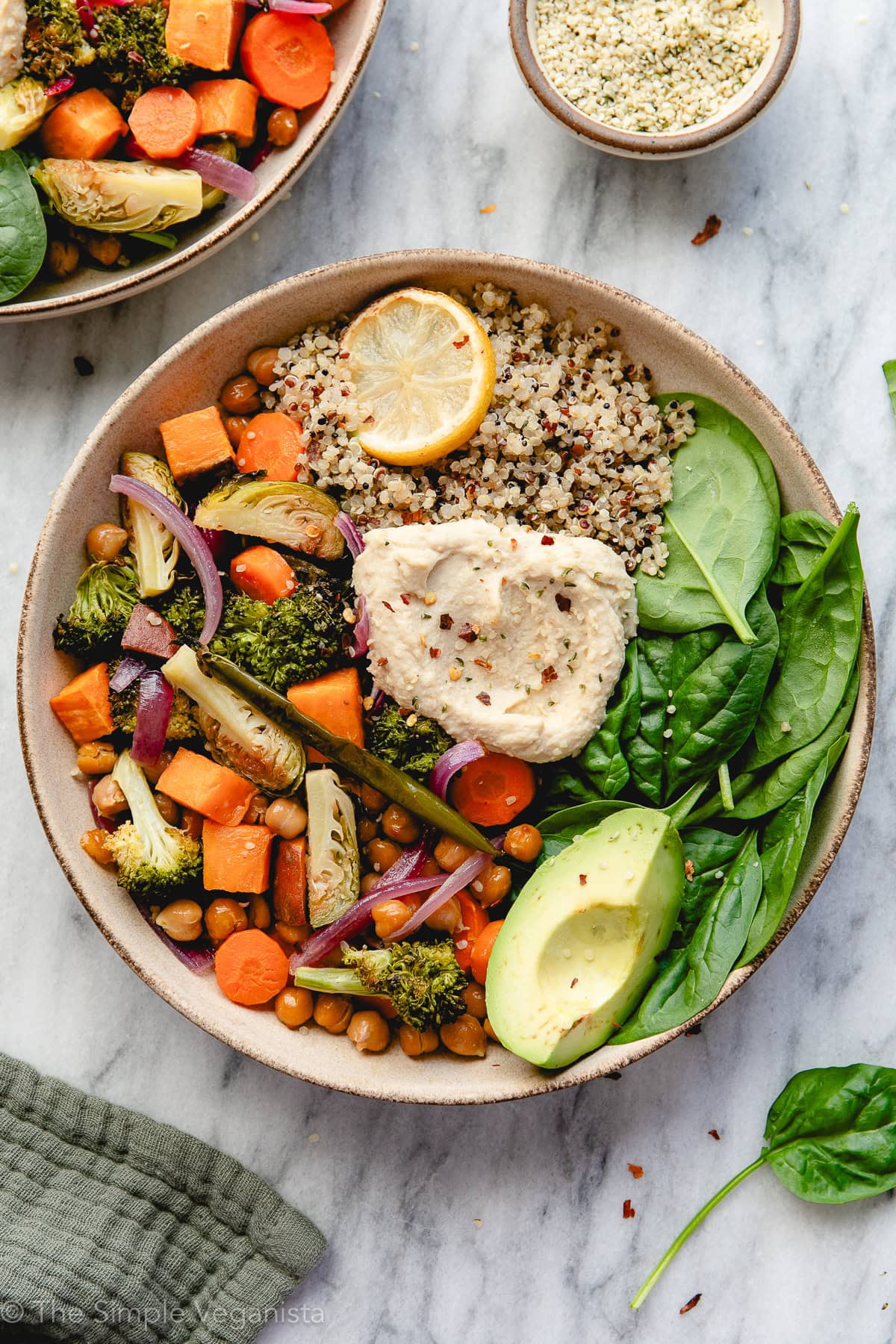 top down view of vegan nourish bowl with quinoa, spinach, hummus, and avocado.