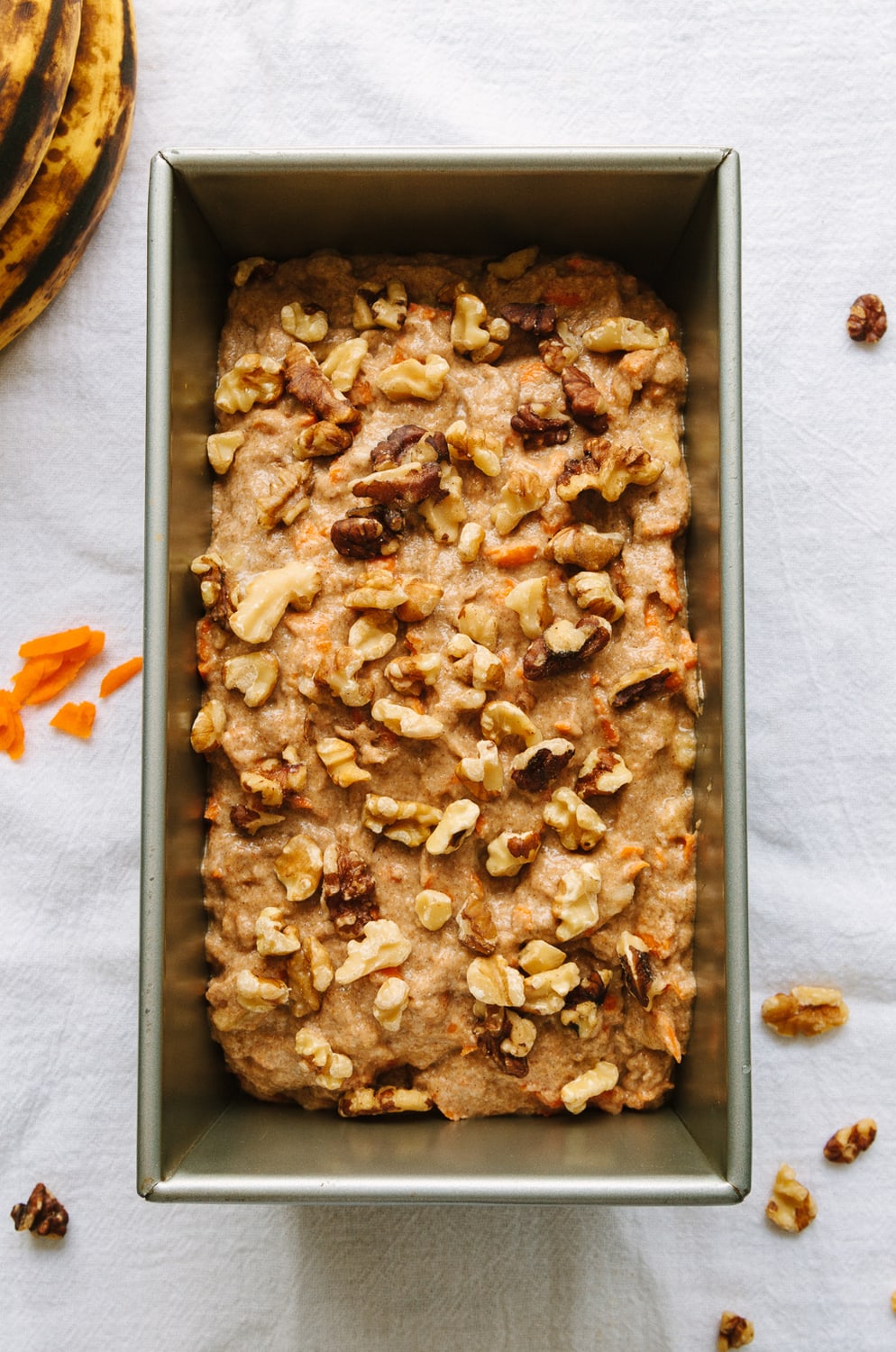 top down view of carrot banana batter added to loaf pan, topped with walnuts and ready for the oven.