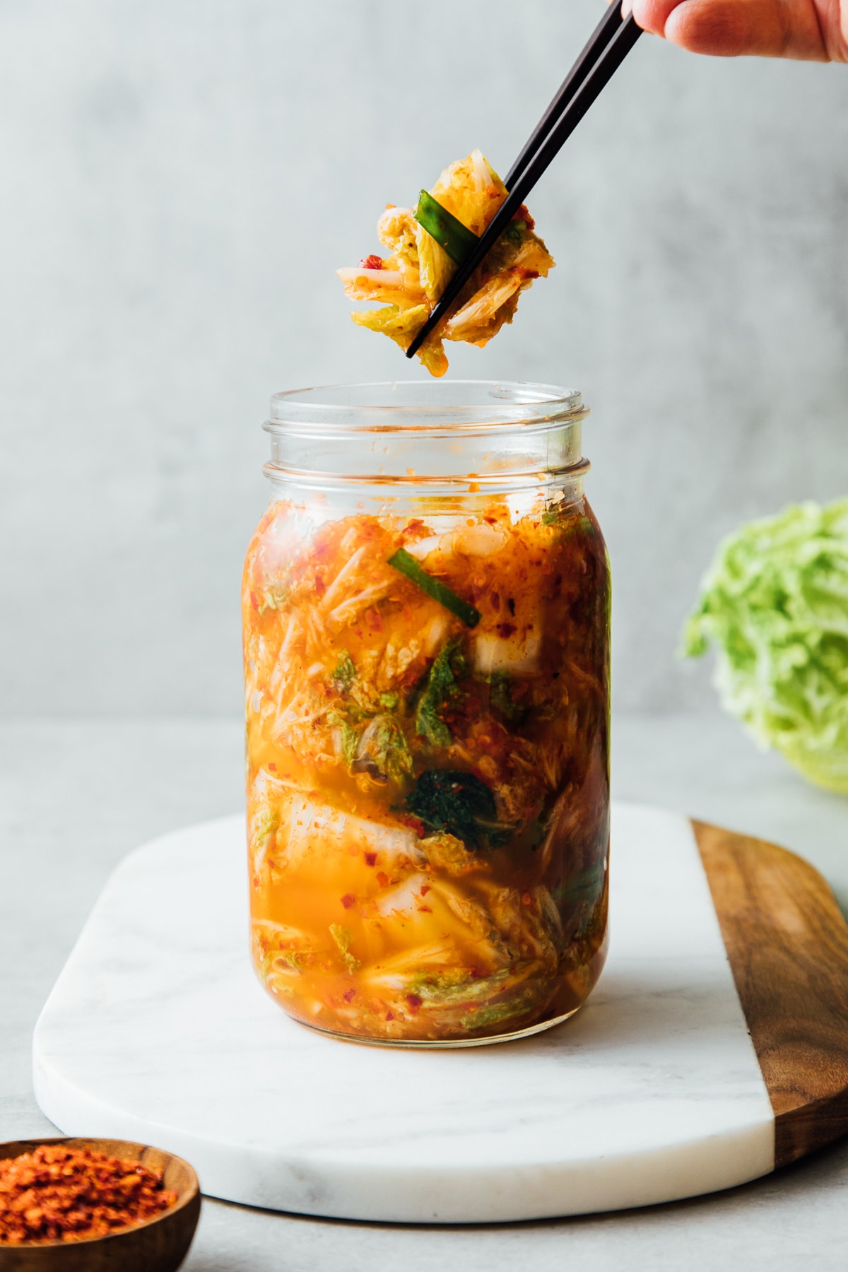 head on view of vegan kimchi in a mason jar with chopsticks.