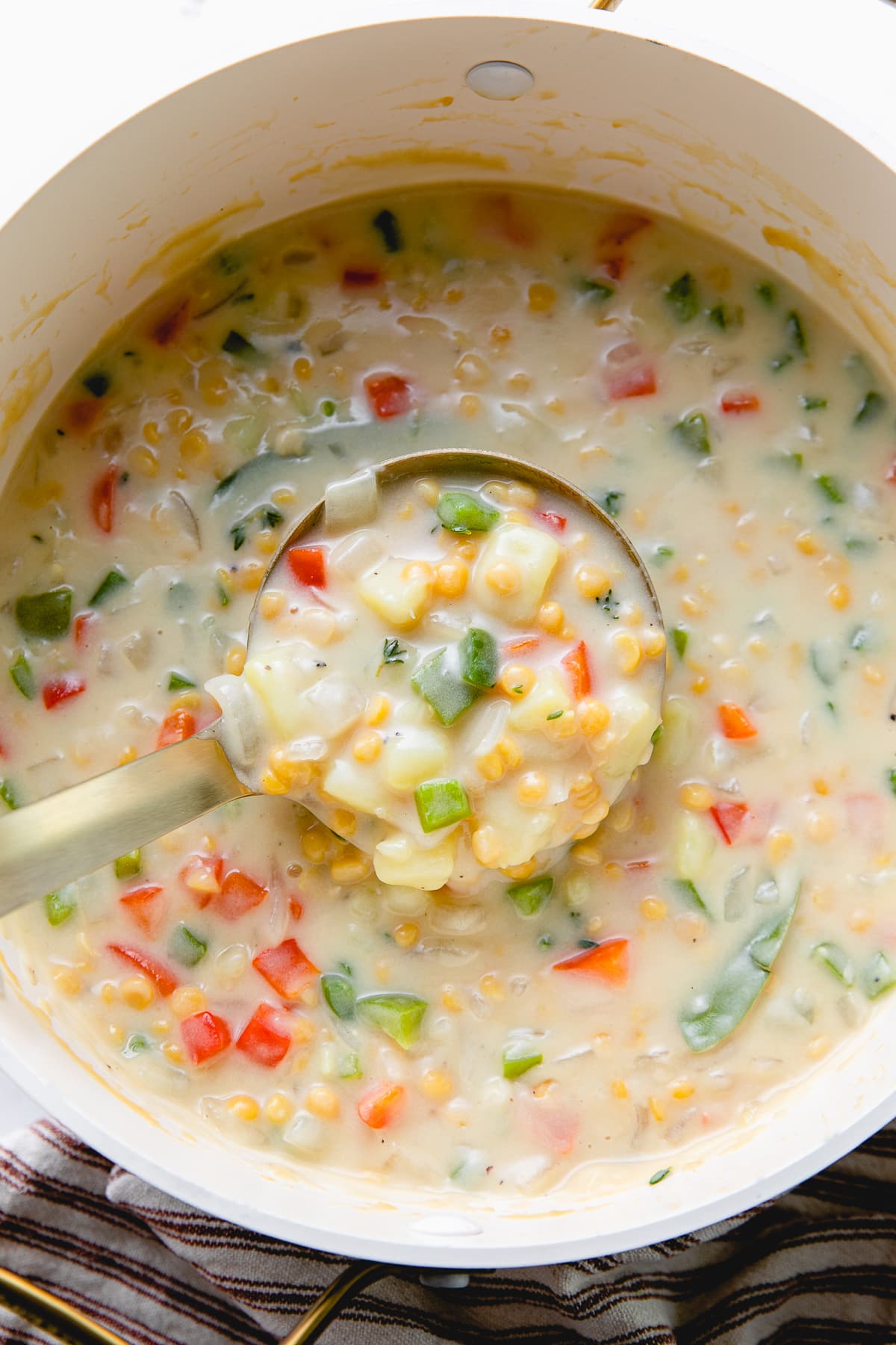 top down view of ladle full of chana dal sweet potato chowder in pot.