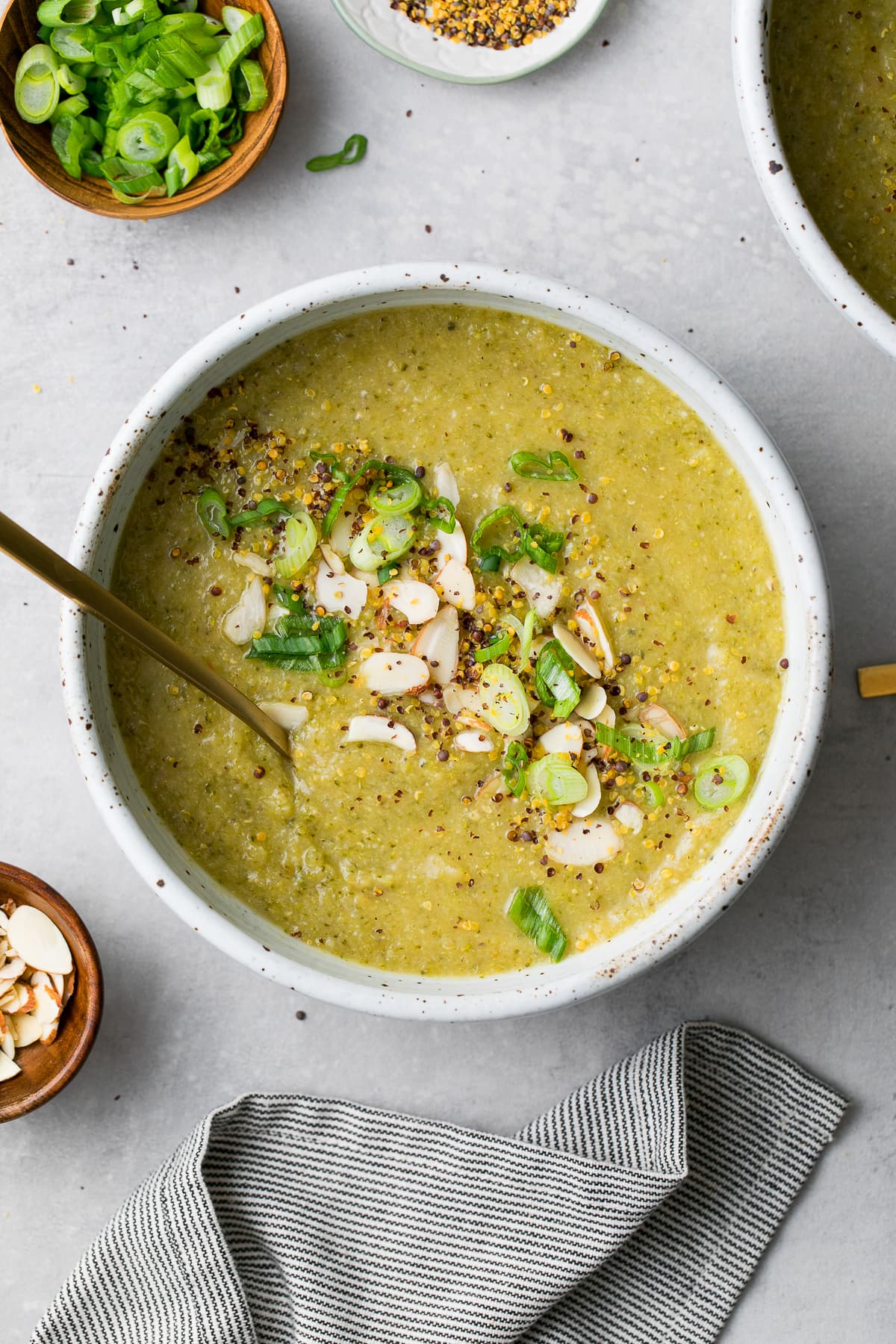 top down view of bowl of creamy broccoli red lentil soup with spoon and items surrounding.