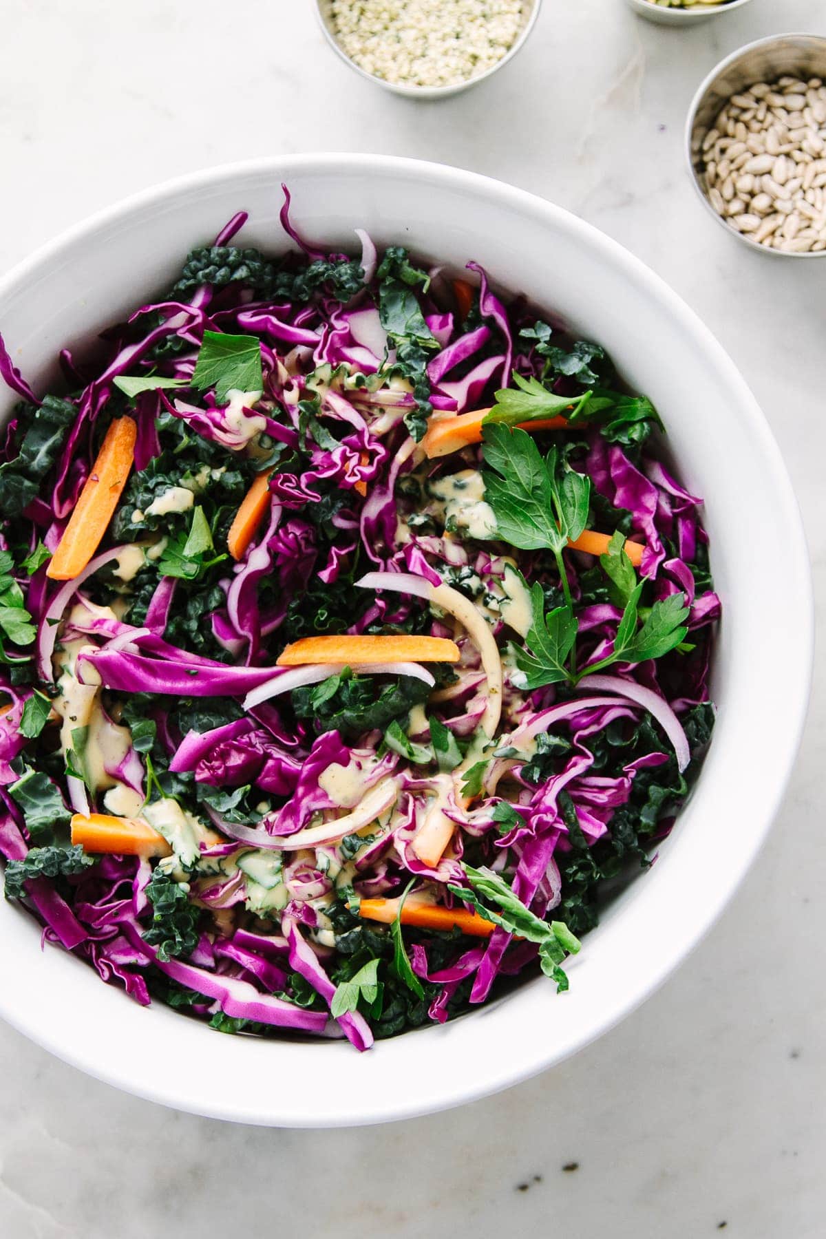 top down view of a mixing bowl with ingredients to make kale red cabbage slaw recipe.