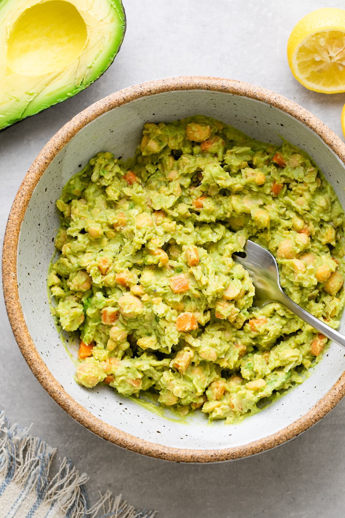 top down view of chickpea avocado salad in a bowl with items surrounding.