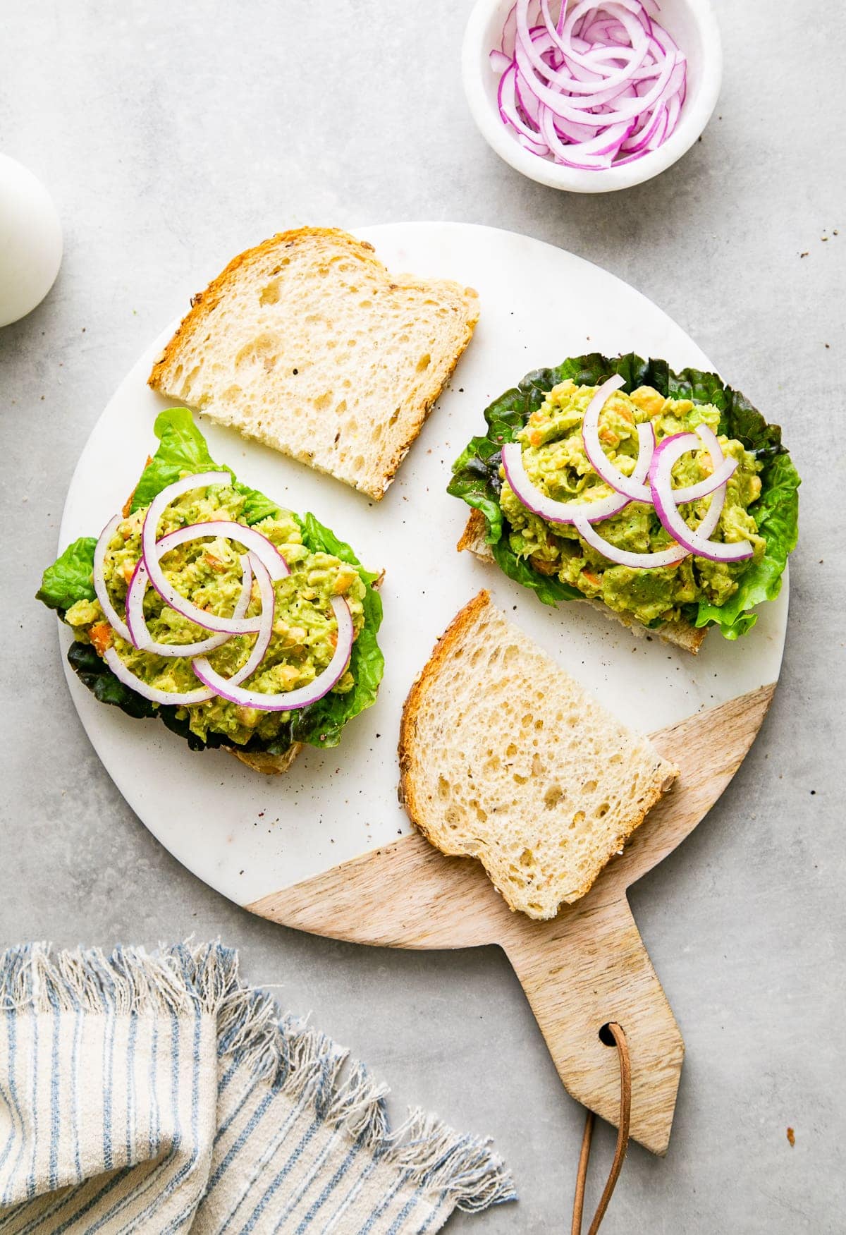 top down view of open faced sandwich halves on round marble serving board.