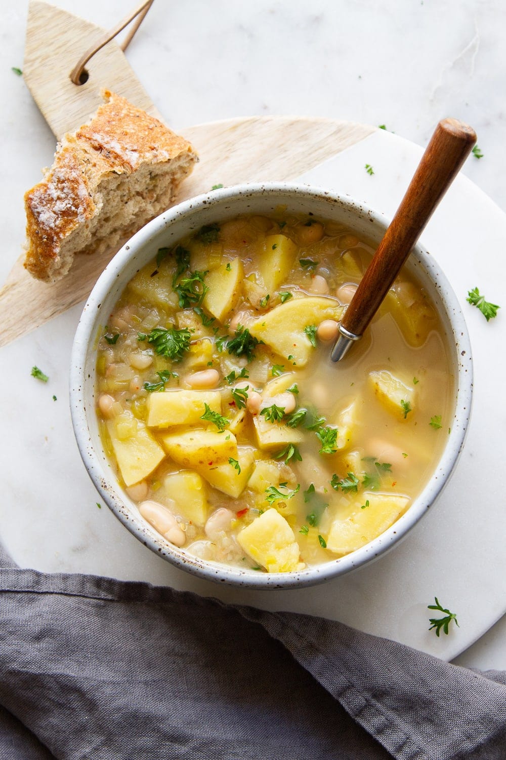 top down view of healthy potato leek and white bean soup in a rustic serving bowl.