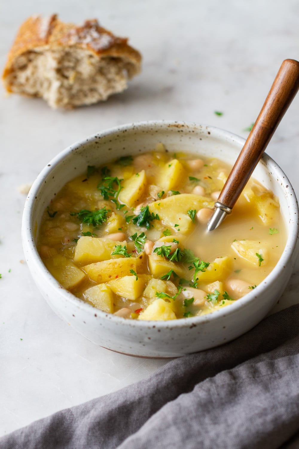 side angle view of healthy potato leek and white bean soup in a rustic serving bowl.