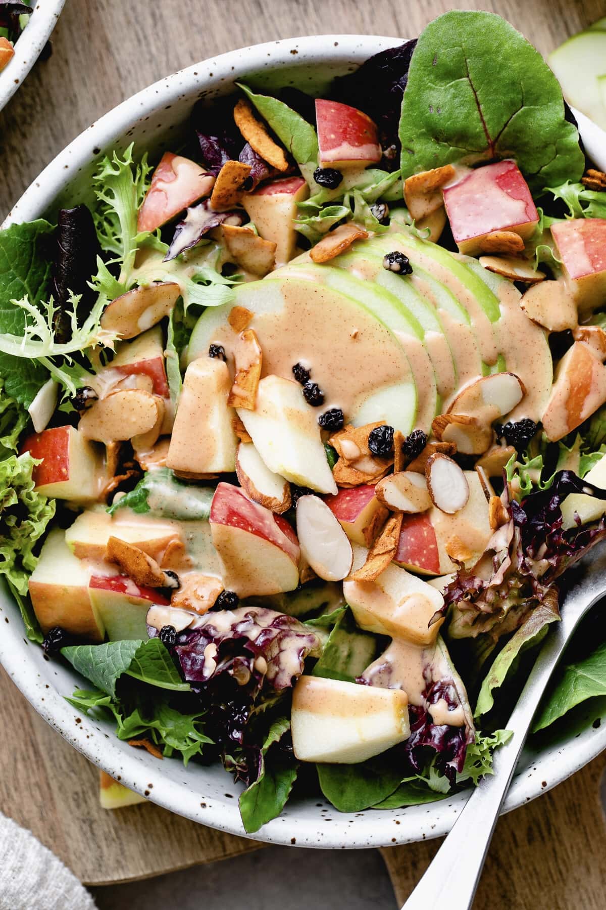 top down view of vegan apple coconut bacon salad with fork and items surrounding.