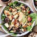 top down view of vegan apple coconut bacon salad with fork and items surrounding.