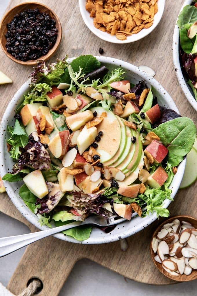top down view of vegan apple coconut bacon salad with fork and items surrounding.