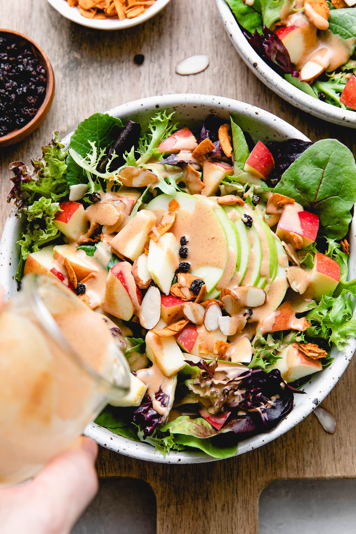 top down view of vegan apple bacon salad being topped with peanut dressing.