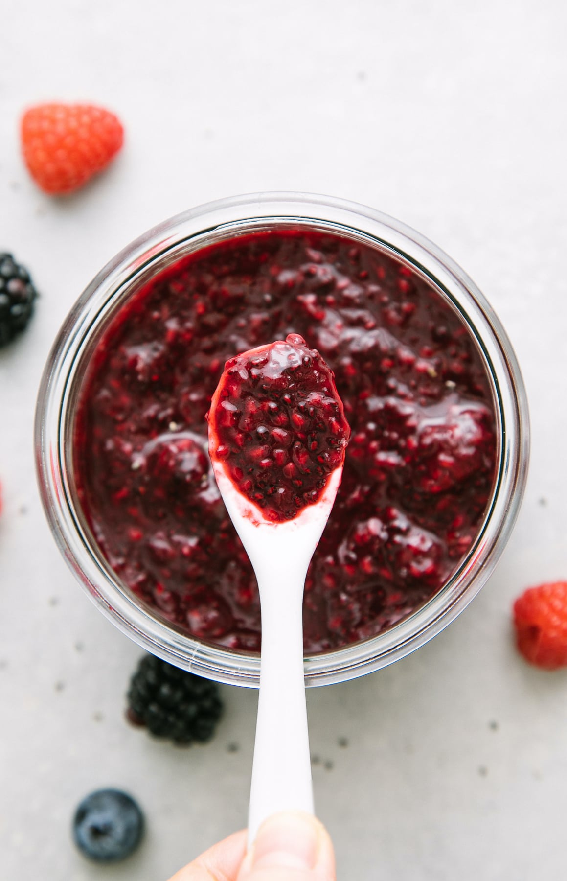 top down view of white spoon with chia jam and items surrounding.