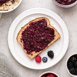 top down view of berry chia seed jam on toast with items surrounding.