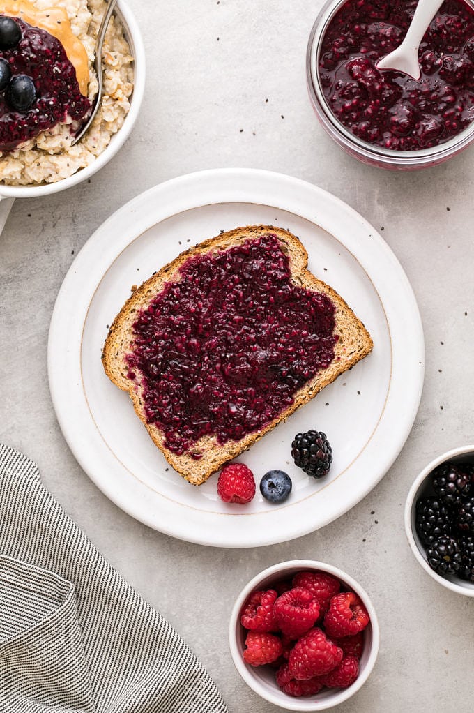 top down view of berry chia seed jam on toast with items surrounding.