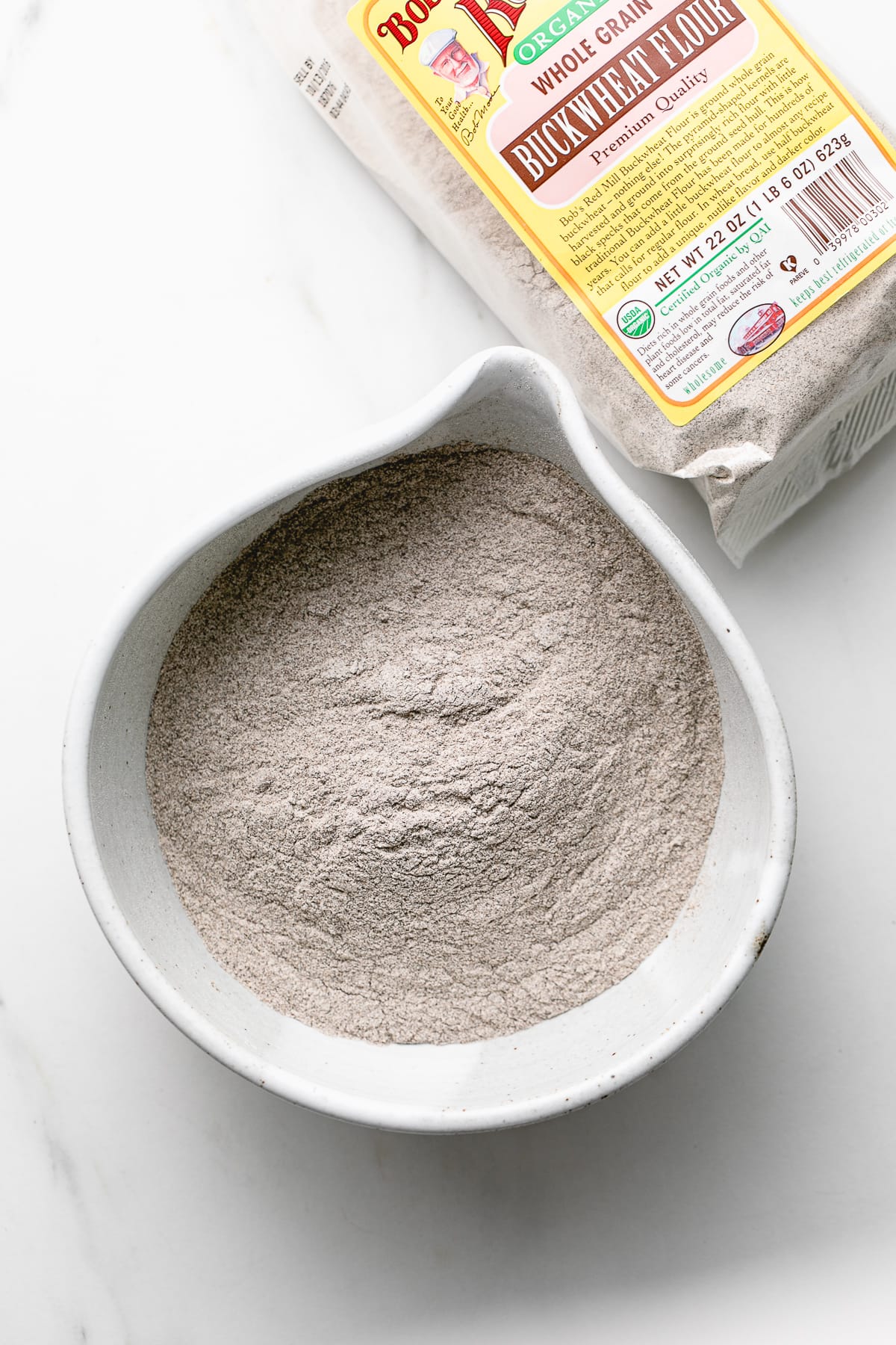 top down view of gluten free buckwheat flour in a bowl with items surrounding.