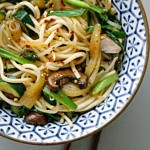 udon noodles with mushrooms and onions in a blue and white bowl