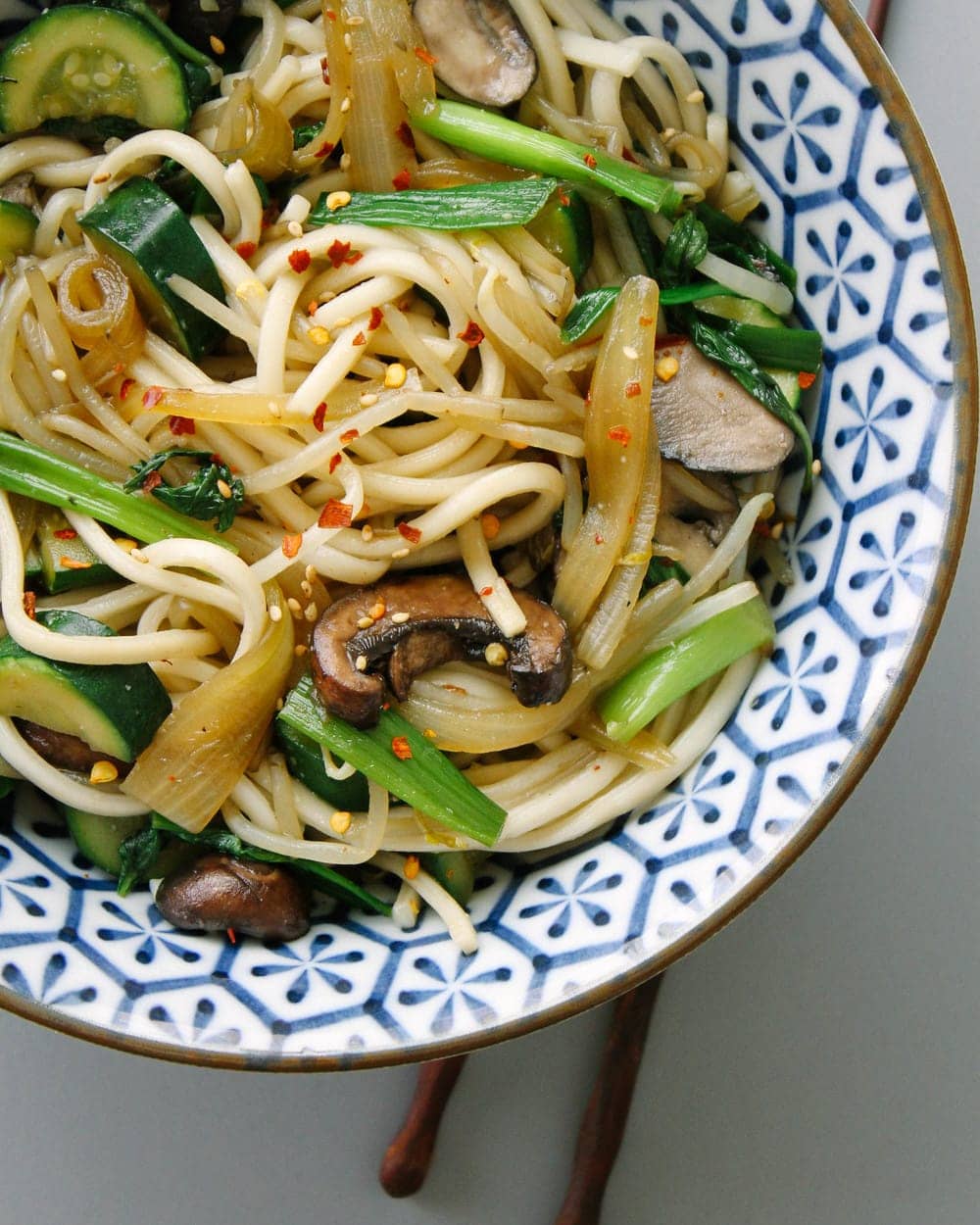 udon noodles with mushrooms and onions in a blue and white bowl