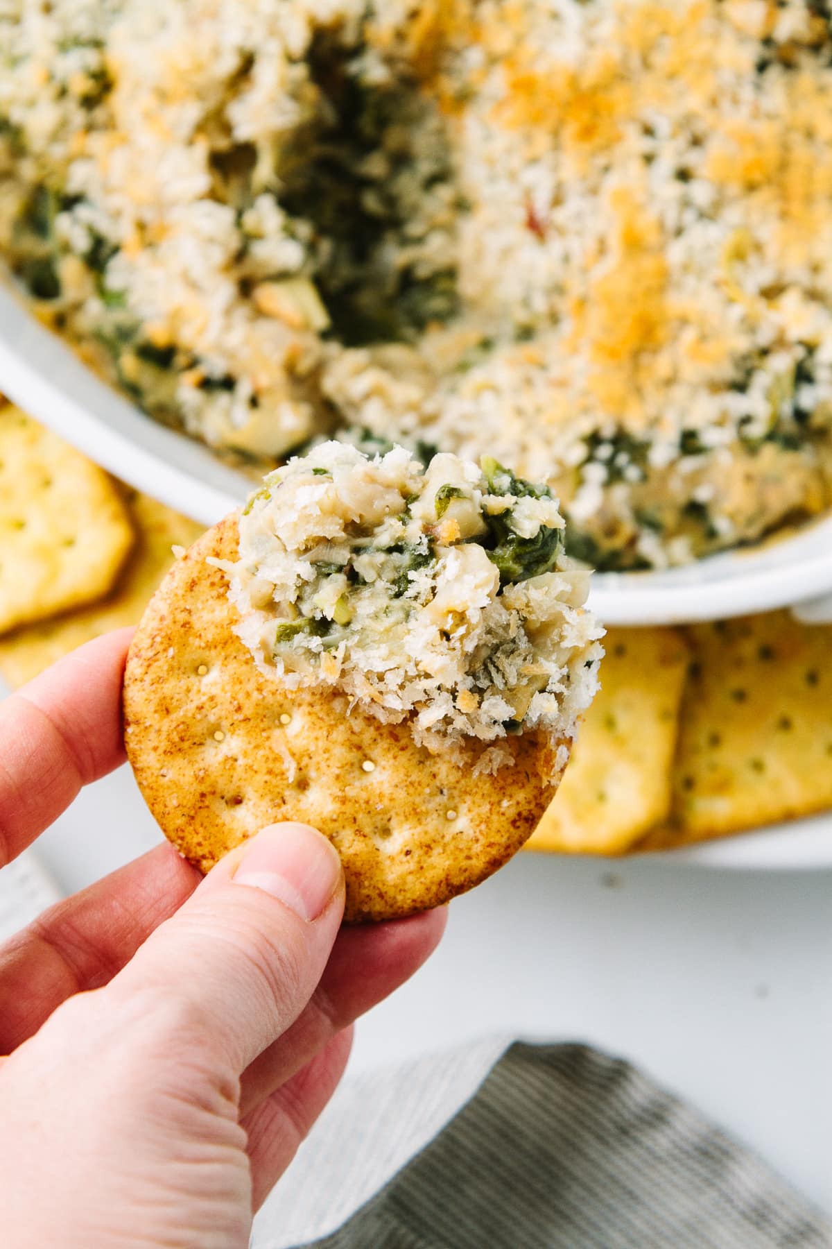 top down view of cracker with a scoop of spinach artichoke white bean dip.