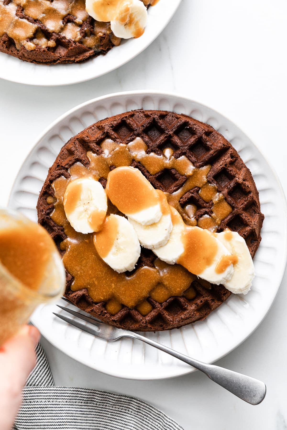 top down view of nut syrup being poured over buckwheat waffles.