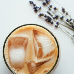 top down view of glass of lavender chai tea with large ice cubes.