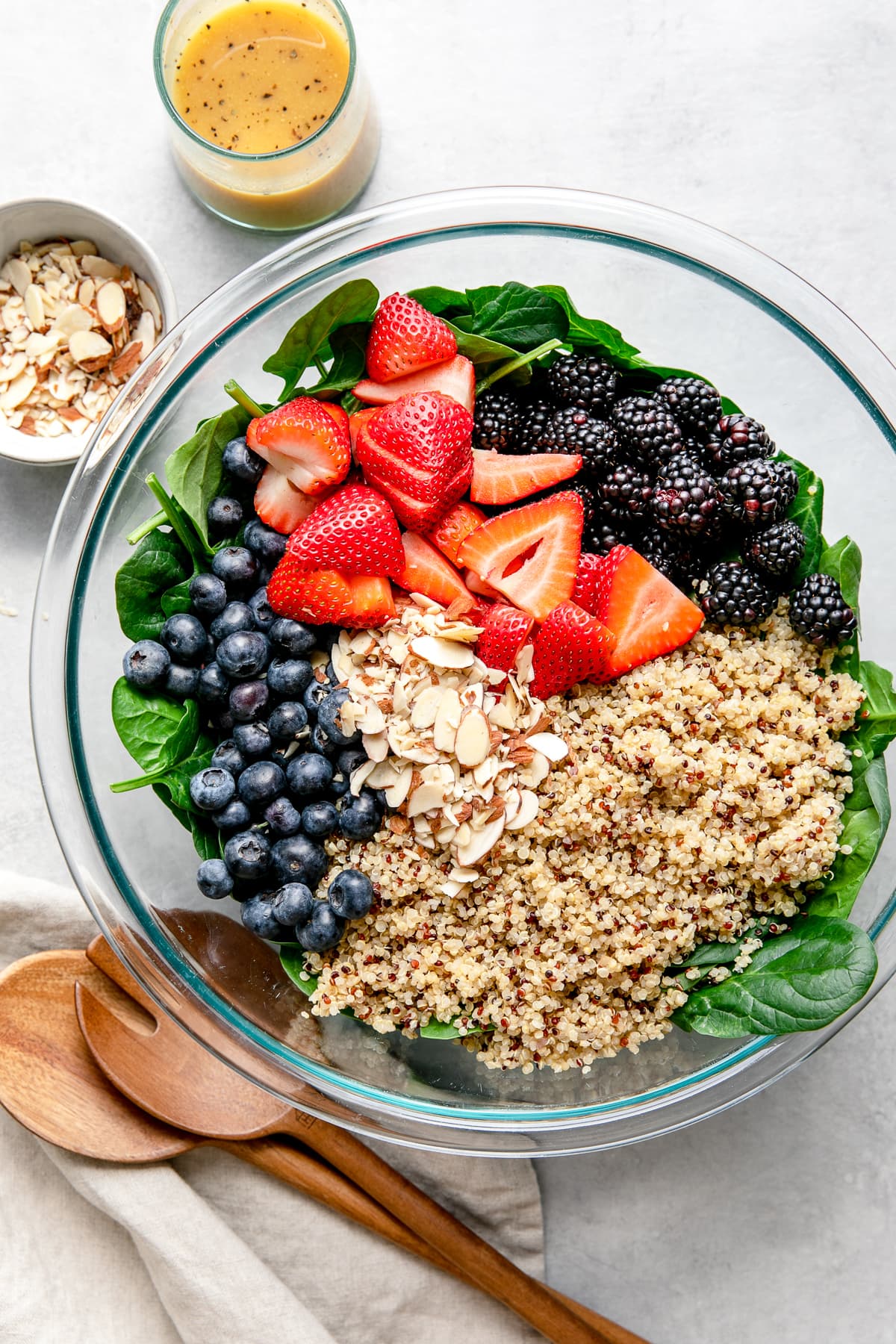 top down view showing the process of assembling berry spinach quinoa salad.