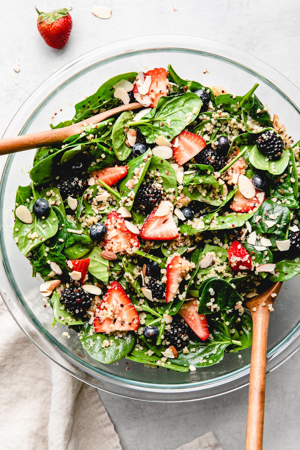 top down view of healthy berry spinach quinoa salad in a glass bowl.