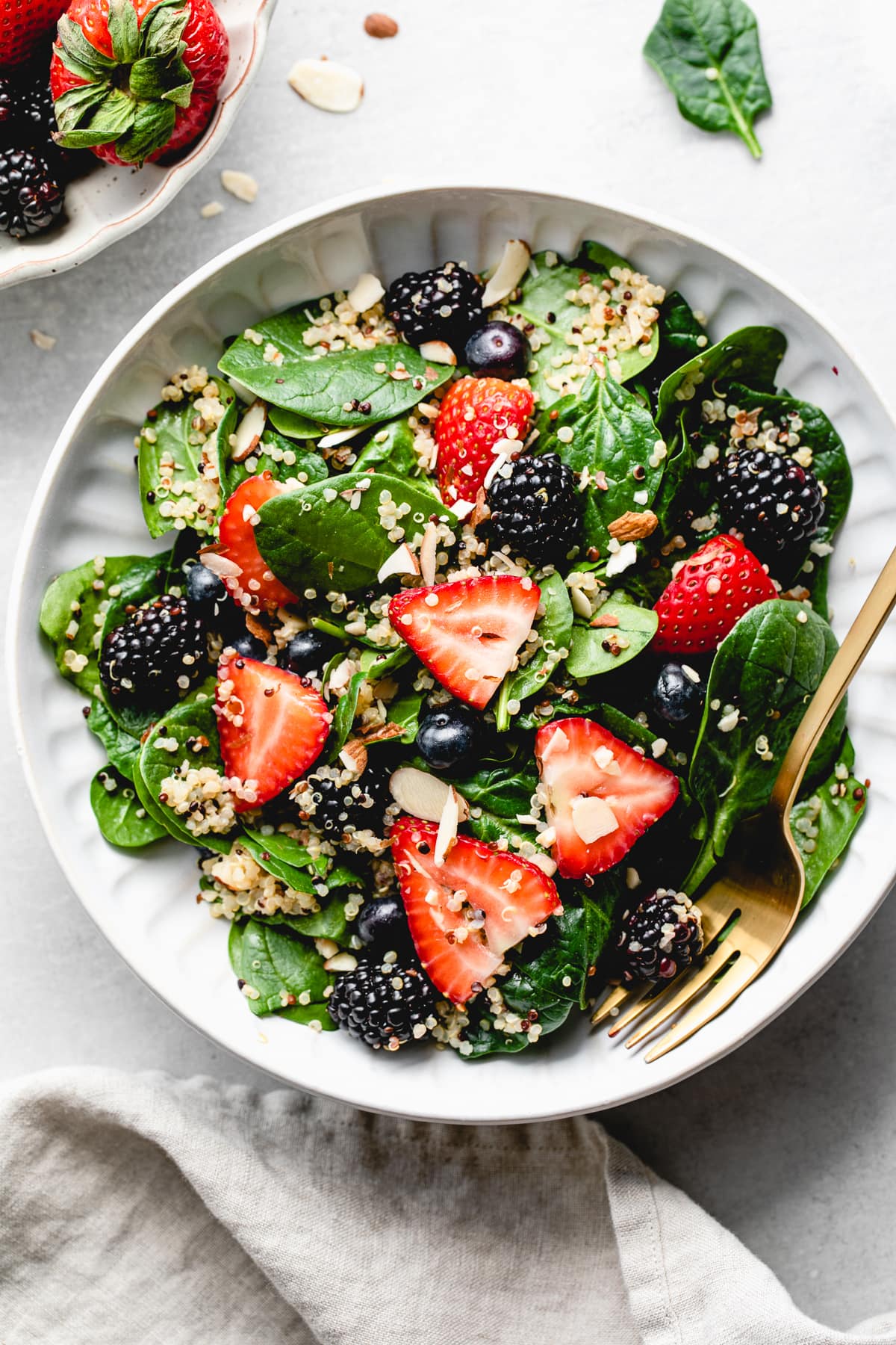 top down view of healthy berry spinach quinoa salad in a bowl.