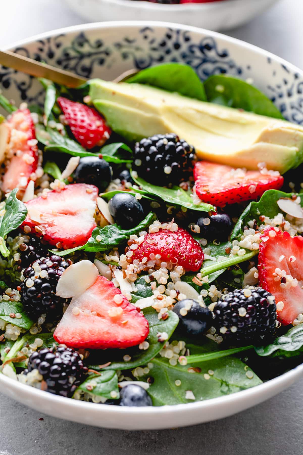 side angle view of healthy berry spinach quinoa salad in a bowl.