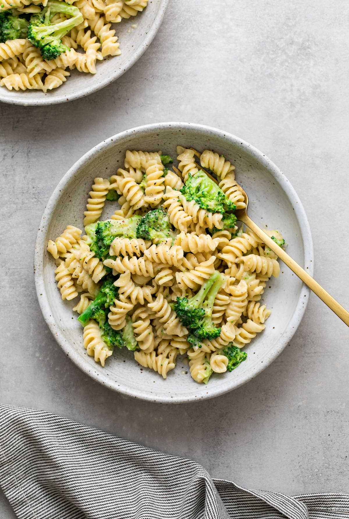 top down view of creamy broccoli pasta with gold spoon.