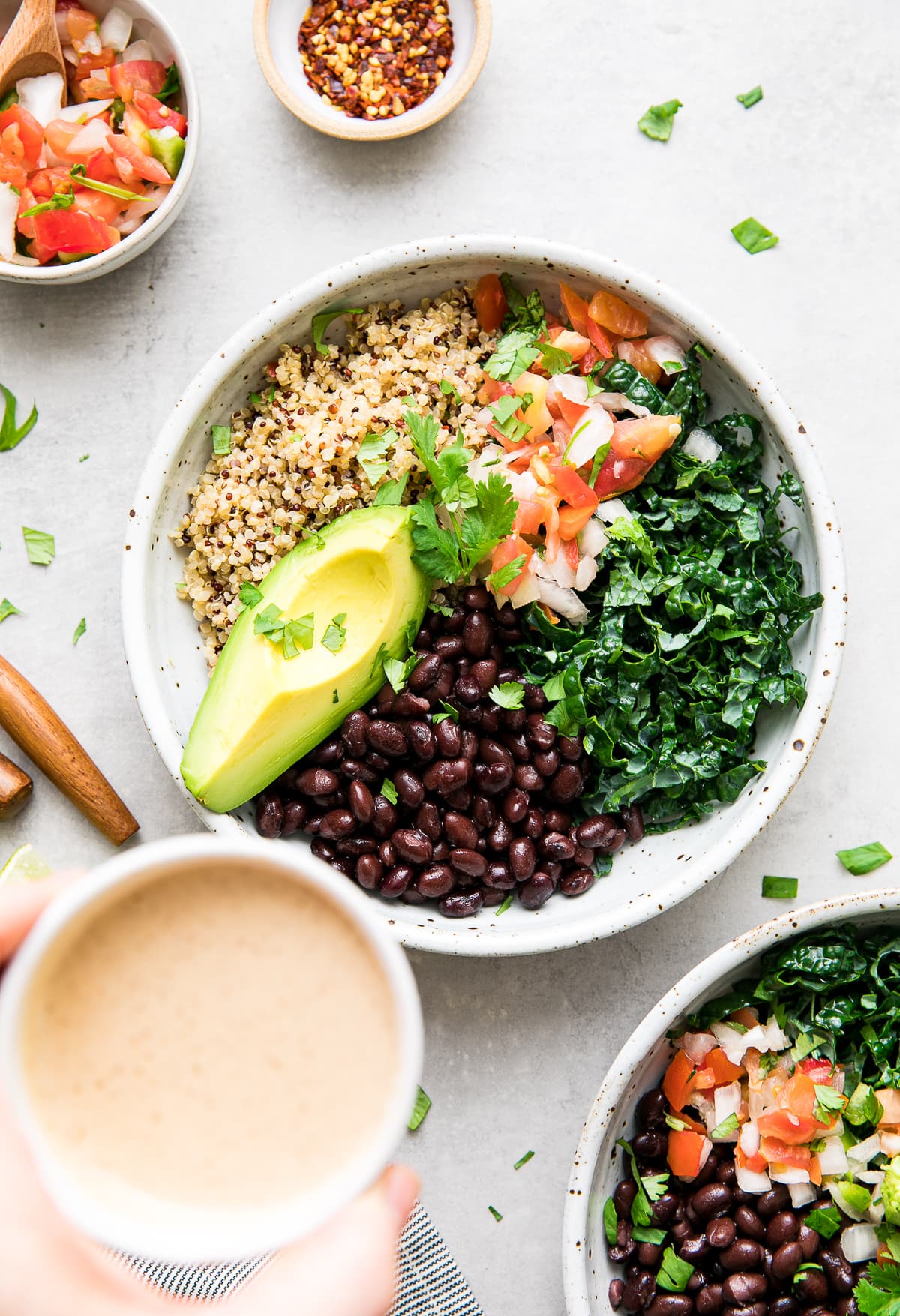 top down view of dressing about to be poured overtop black bean burrito bowl with item surrounding.