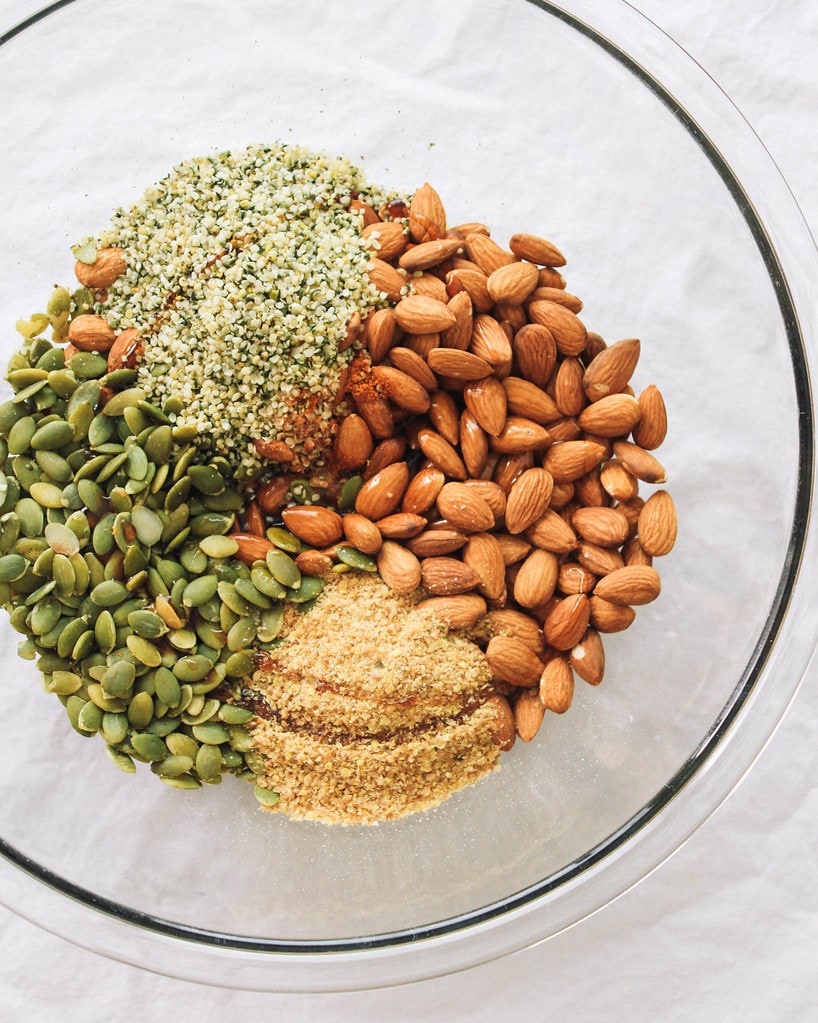 ingredients for healthy spicy nut and seed protein bars in a glass bowl before mixing.