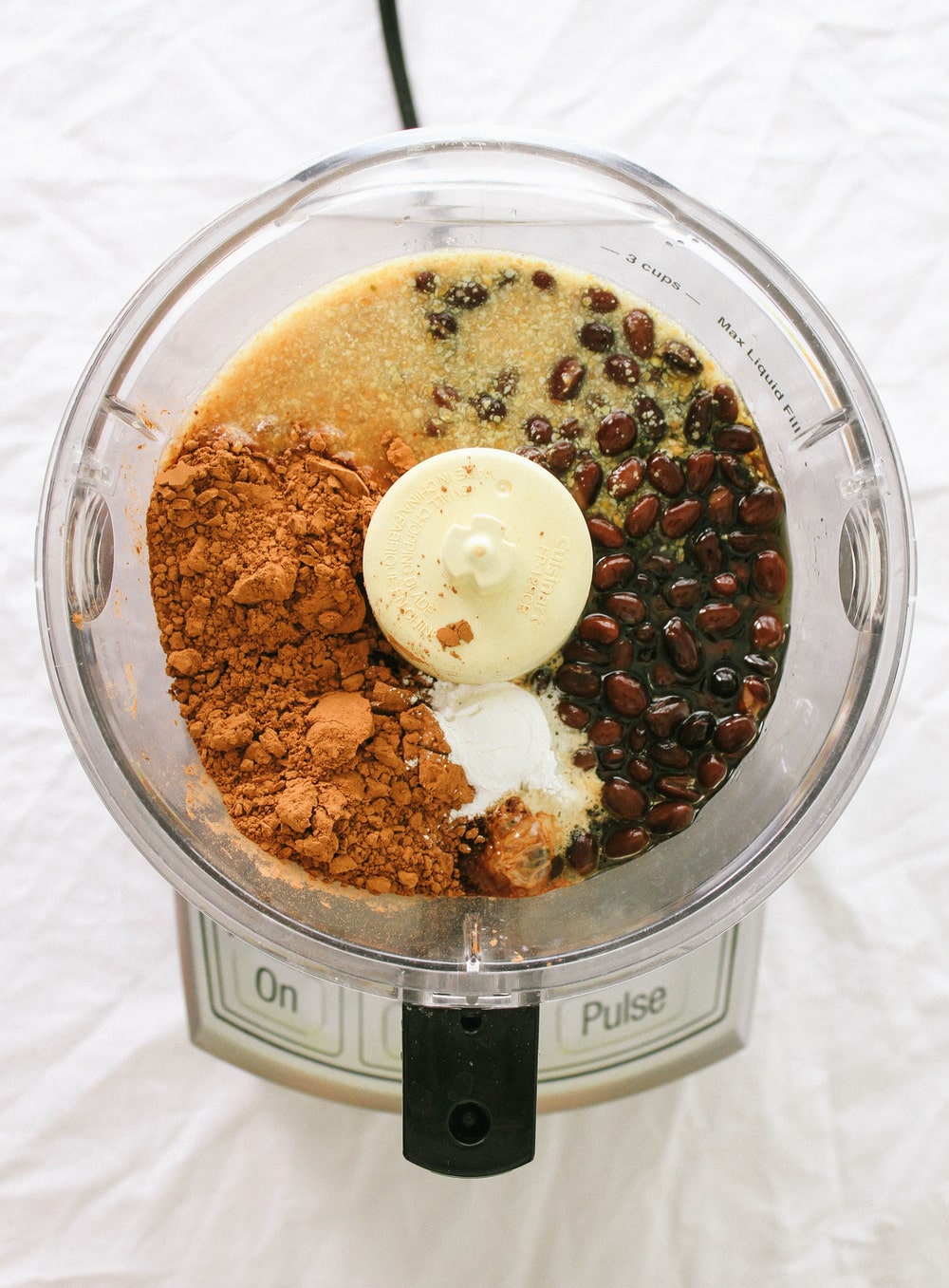 top down view of ingredient for black bean brownies added to bowl of a food processor.