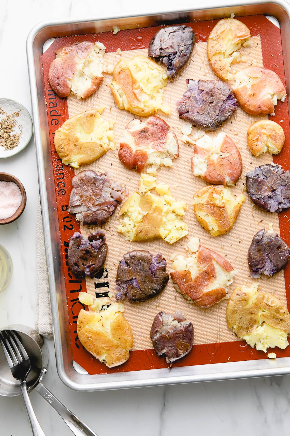 top down view of roasted potatoes freshly smashed with items surrounding.