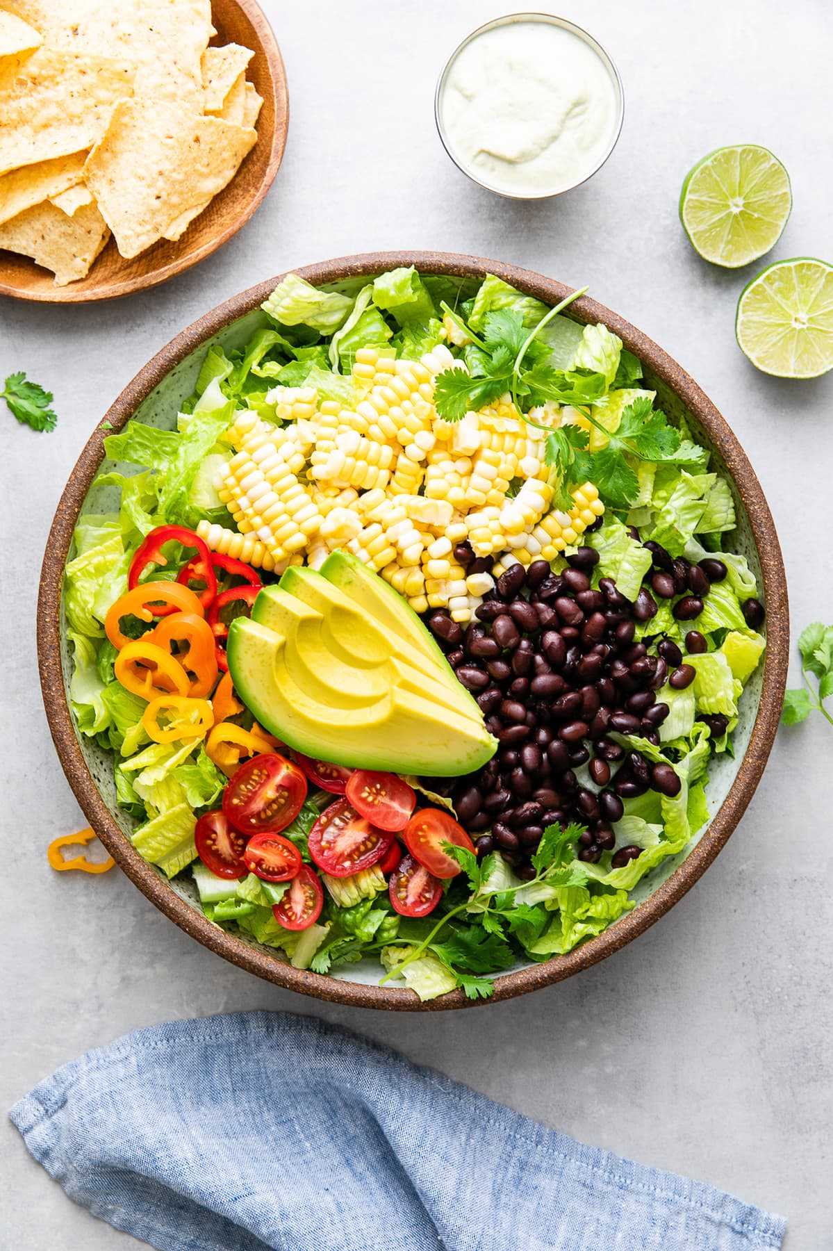 top down view of bowl filled with the ingredients to make vegan southwest salad with items surrounding.