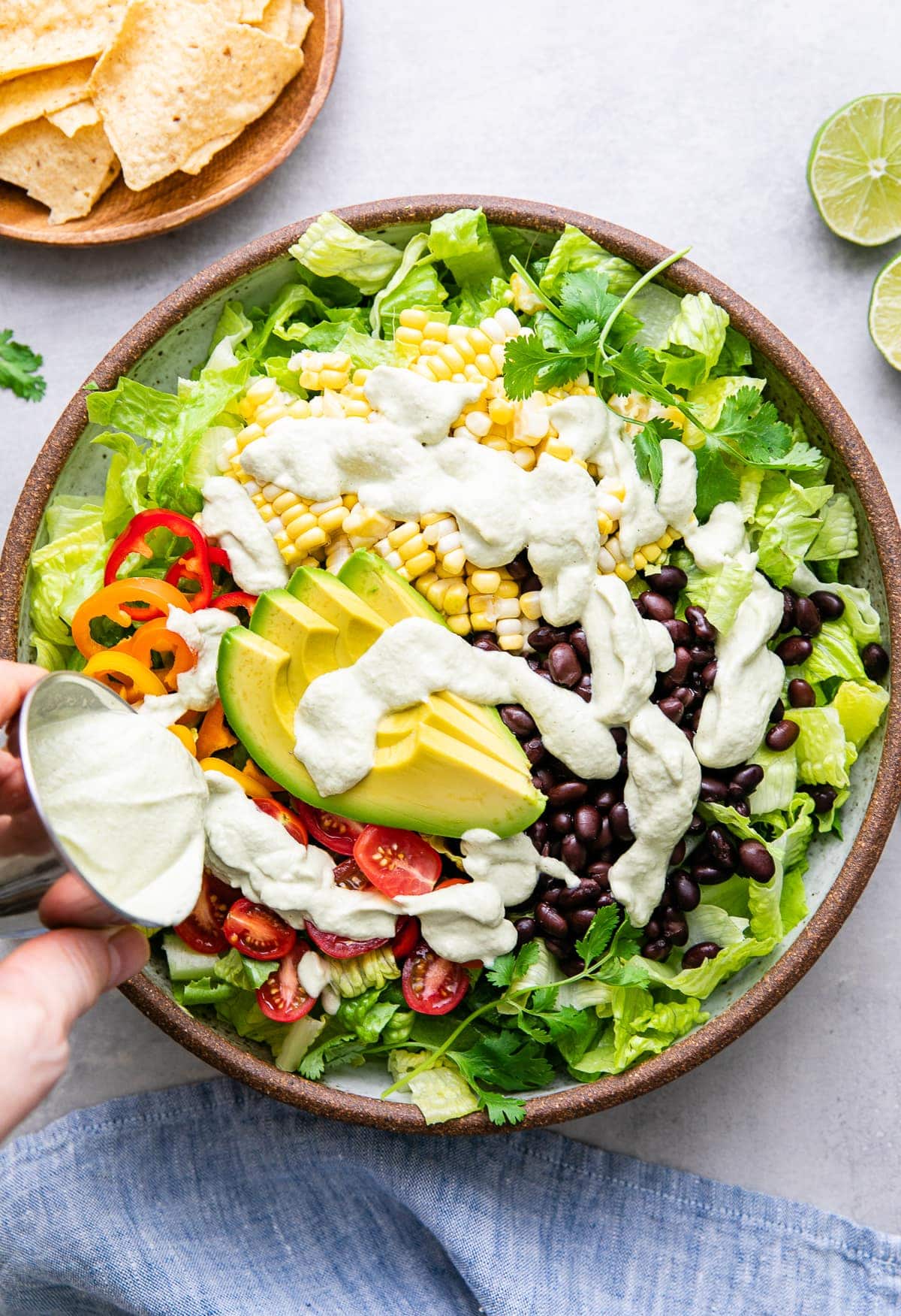 top down view showing creamy hatch ranch dressing being poured over southwestern salad.