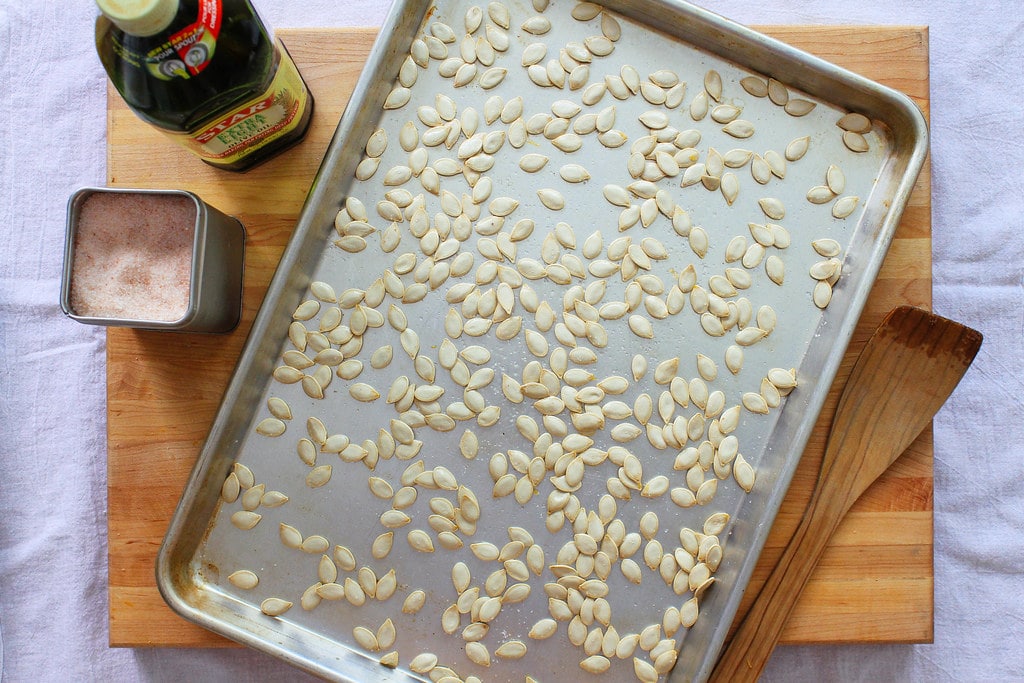 top down view of prepped pumpkin seeds on a baking sheet ready for the oven.