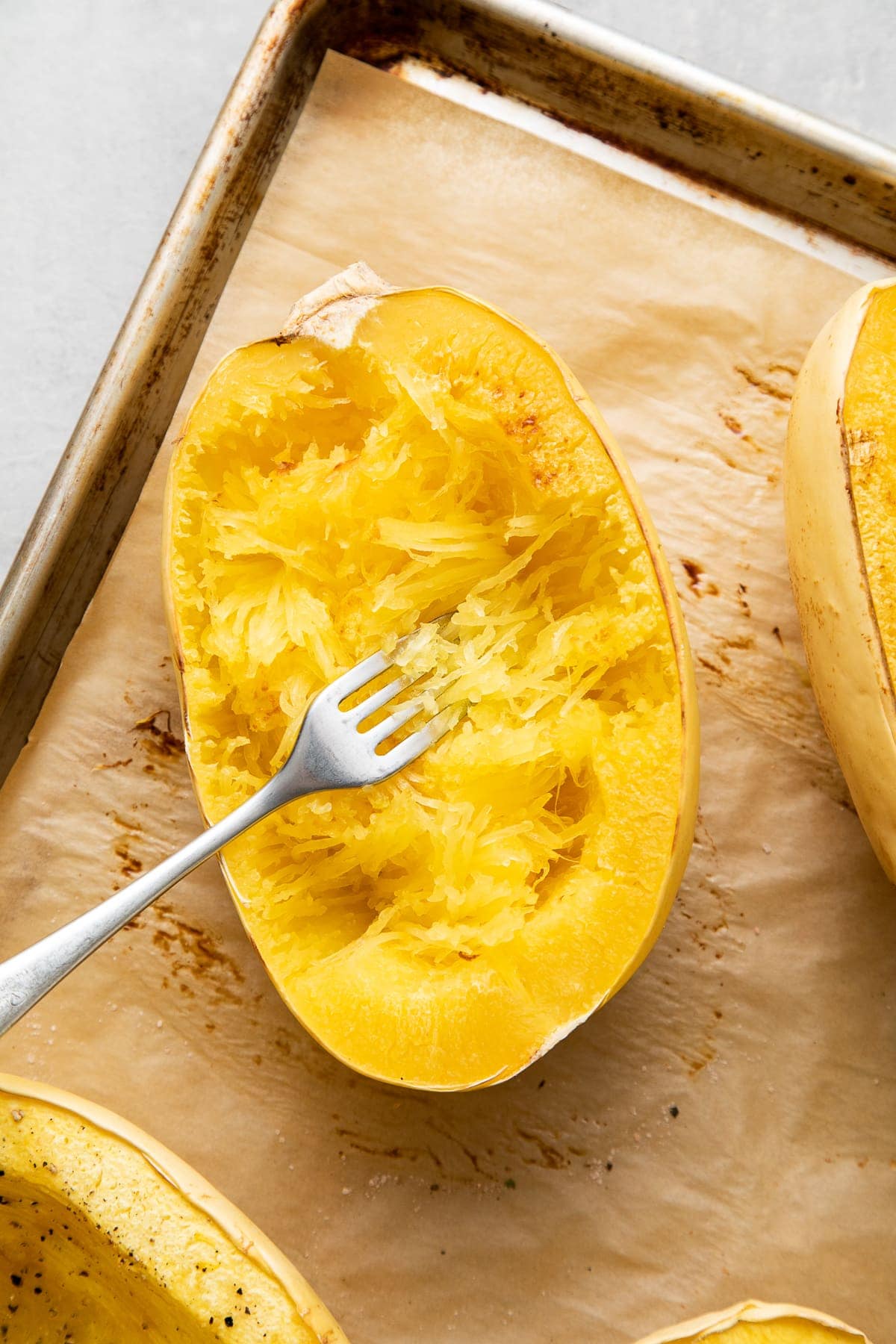 top down view showing the process of scraping spaghetti squash from side to side using a fork.