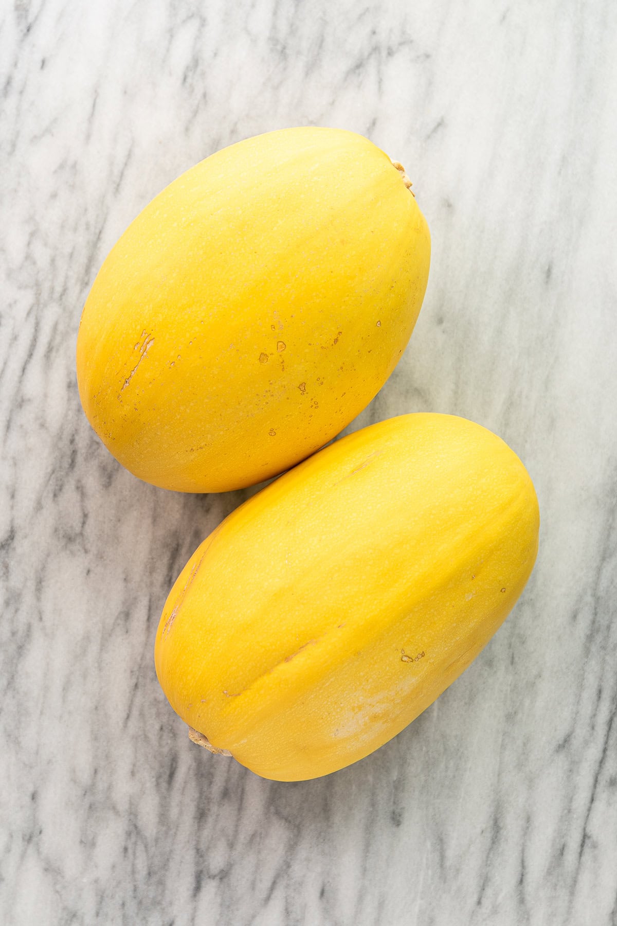 top down view of 2 spaghetti squash on a marble slab.