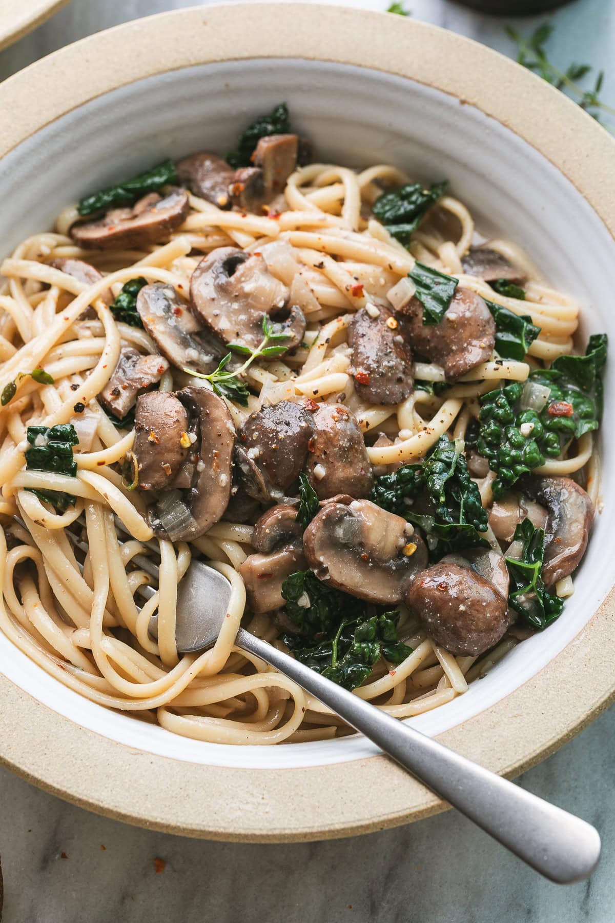 side angle view of bowl with freshly made mushroom and kale pasta.