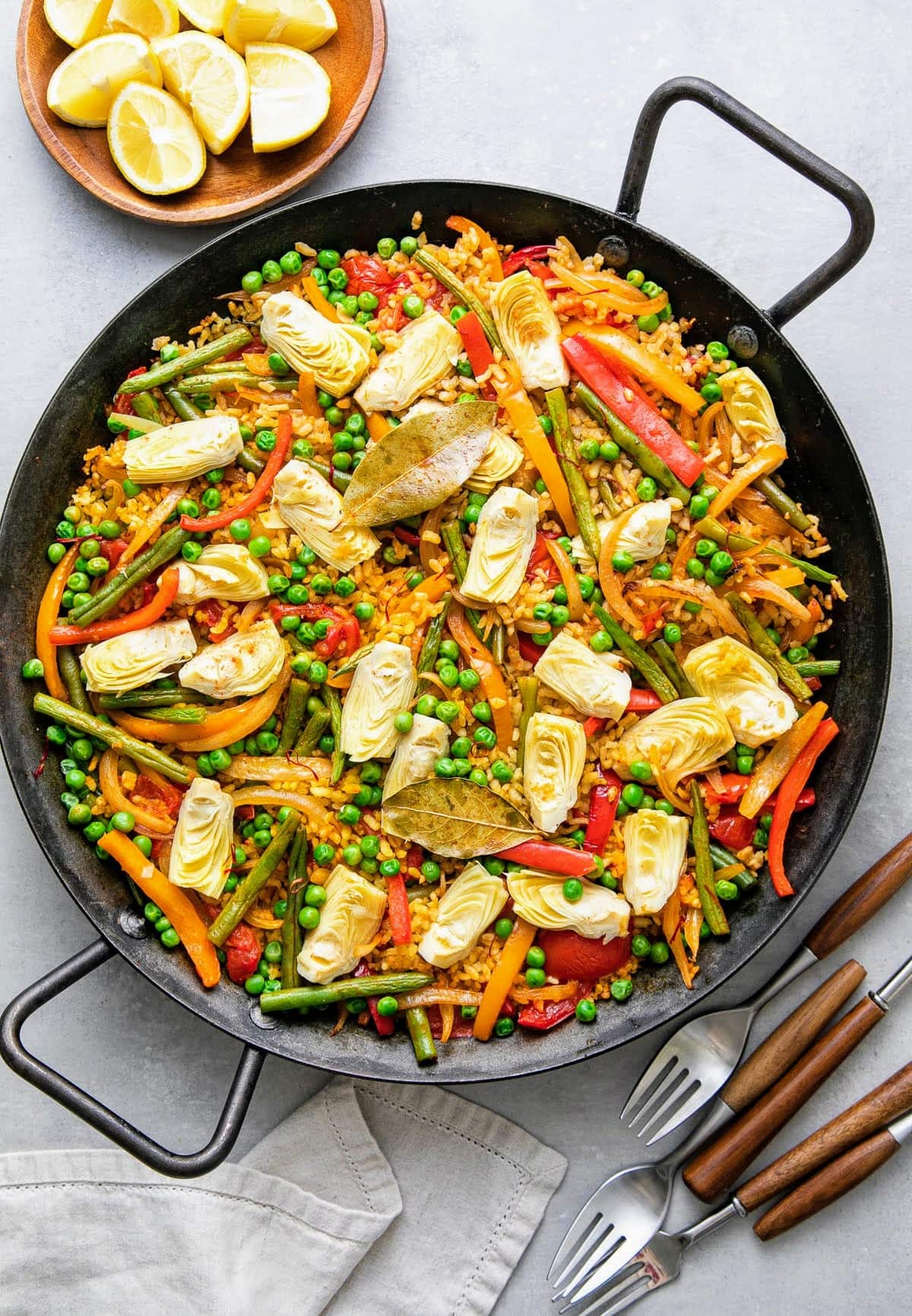 top down view of vegetable vegan paella in a paella pan with items surrounding.