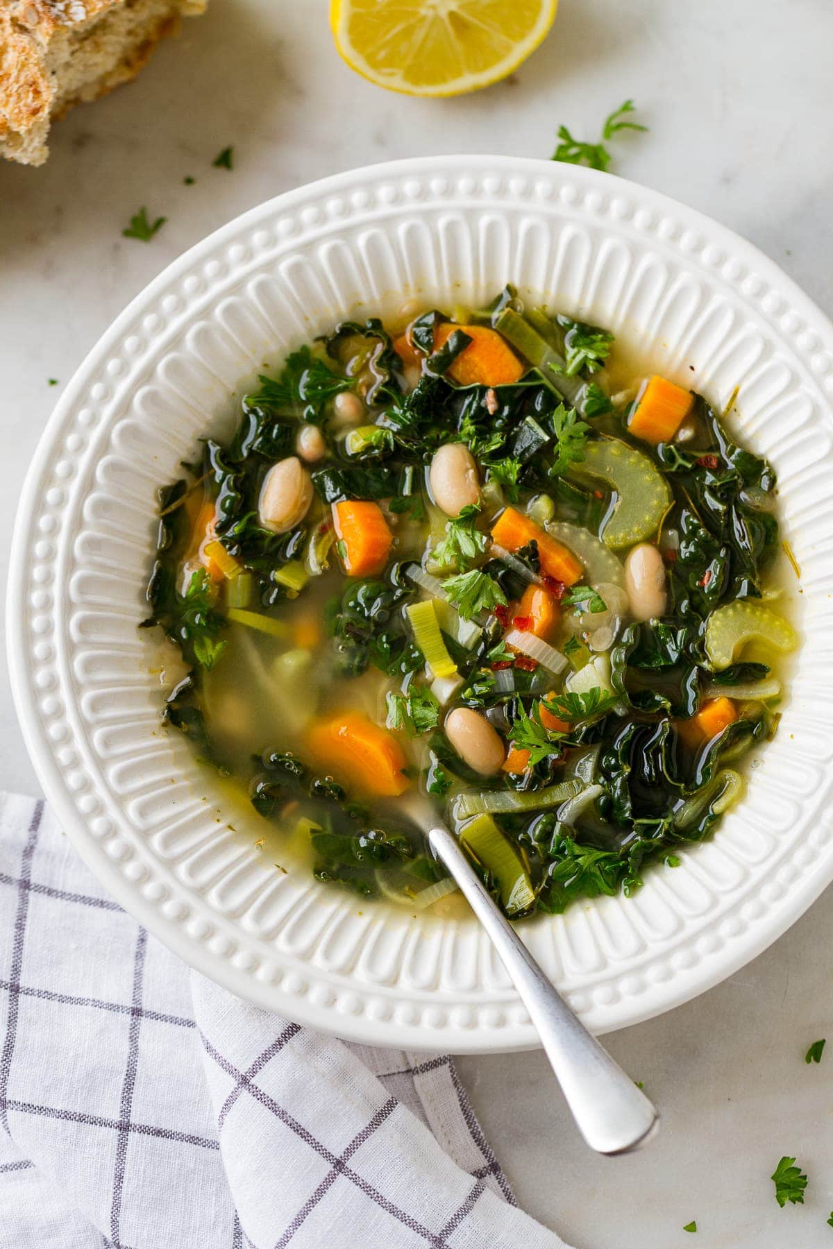 top down view of lemon kale white bean soup in a bowl with spoon.