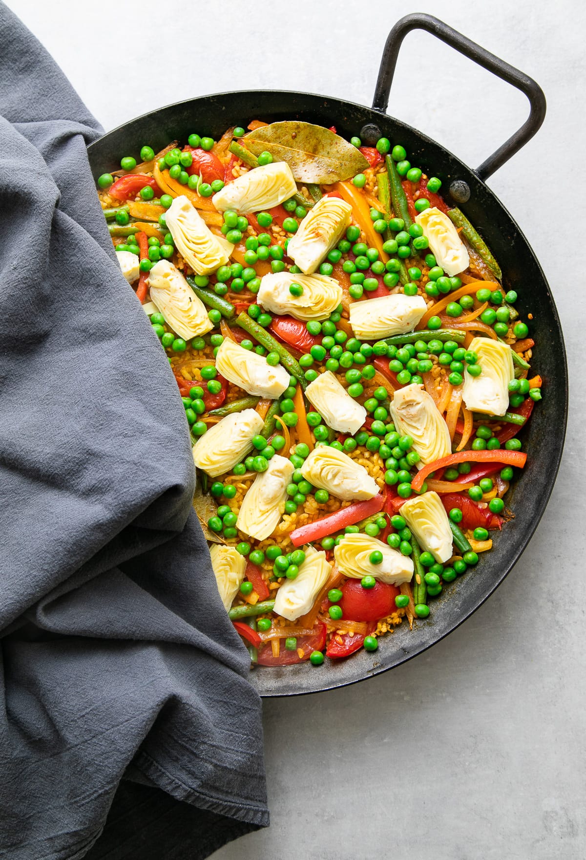 top down view showing veg broth poured over rice and veggies in paella pan.
