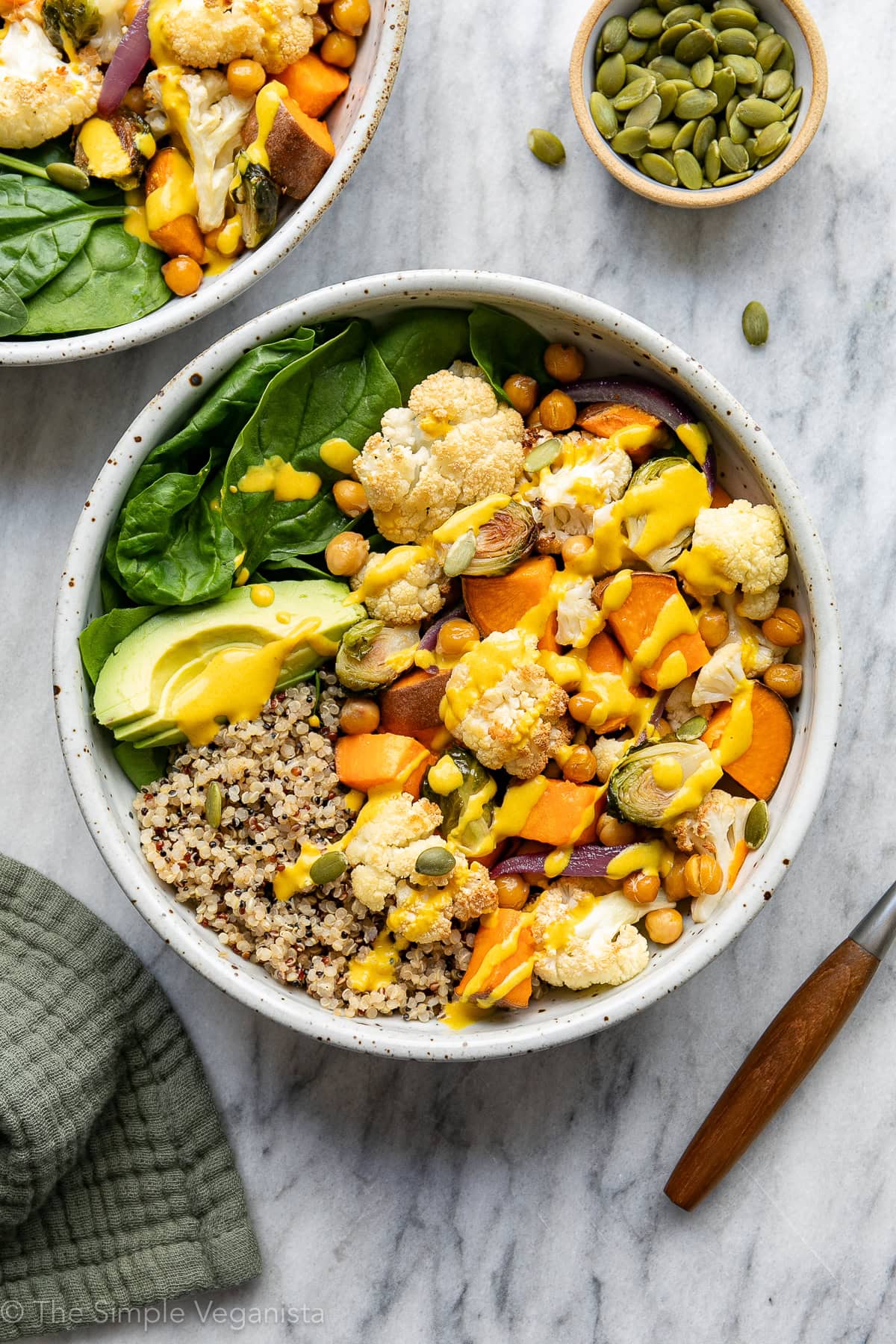 plated cauliflower sweet potato bowl with turmeric dressing and items surrounding.