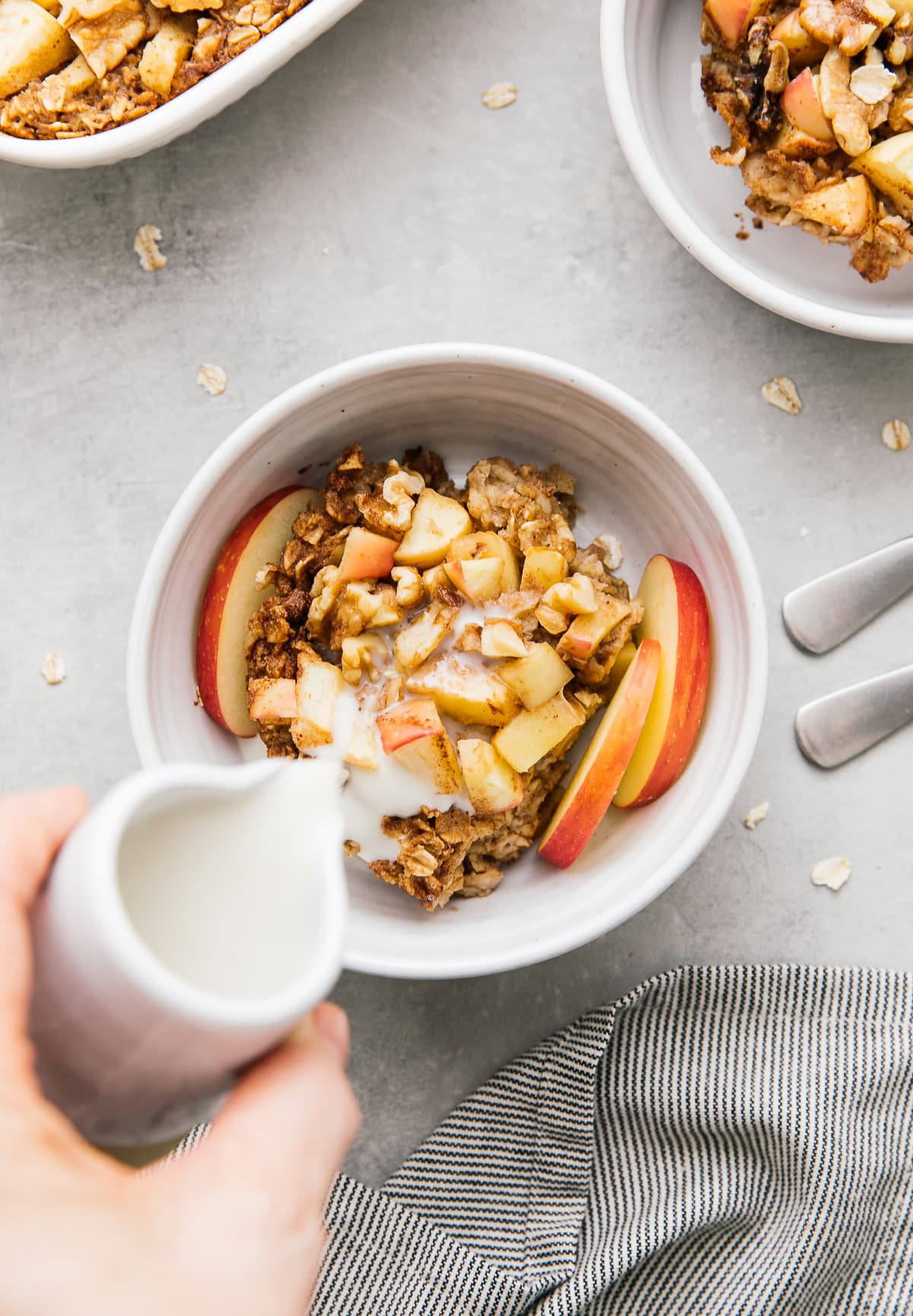 top down view of milked being poured over plated cinnamon apple baked oatmeal.