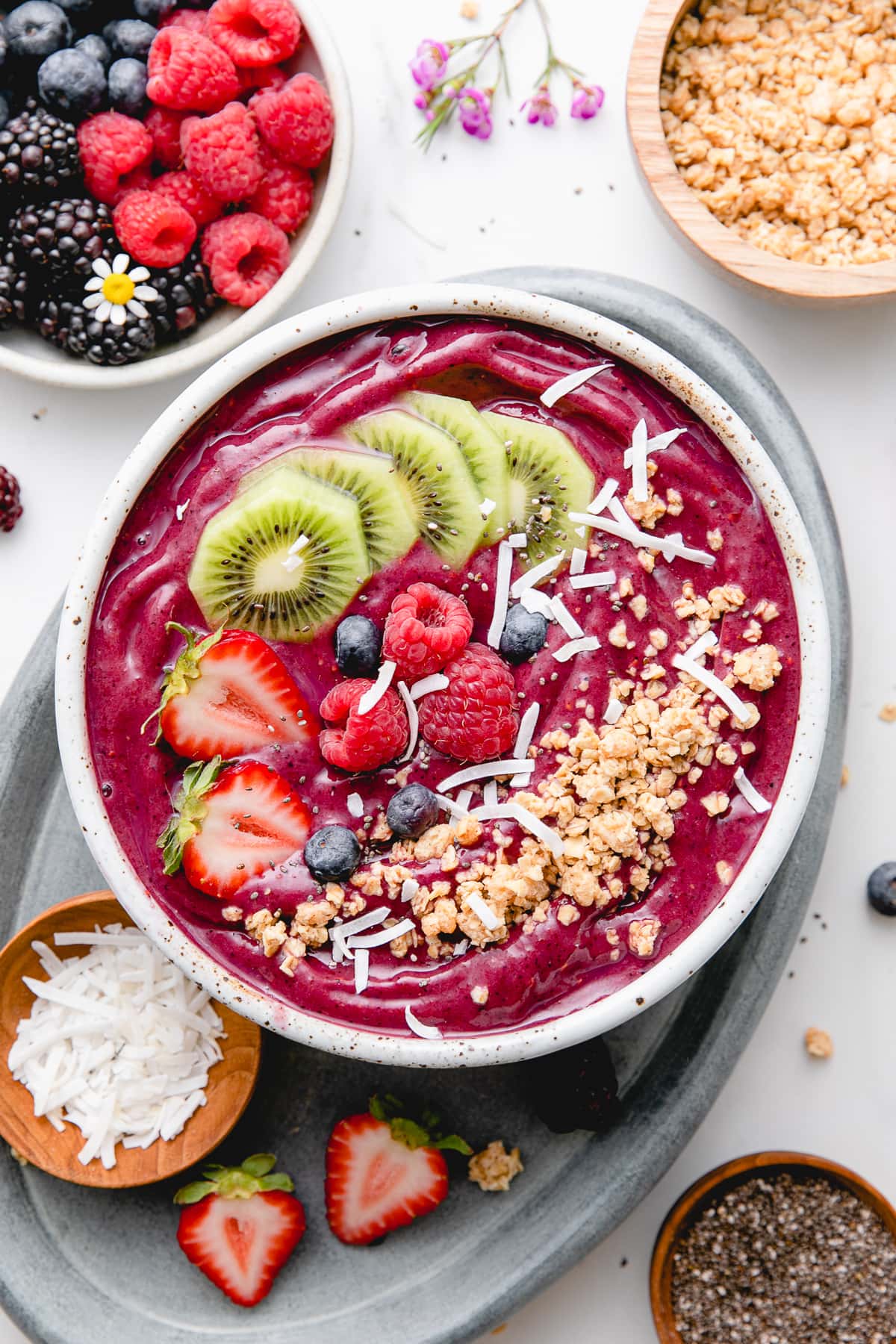 top down view of homemade acai bowl topped with healthy toppings with items surrounding.